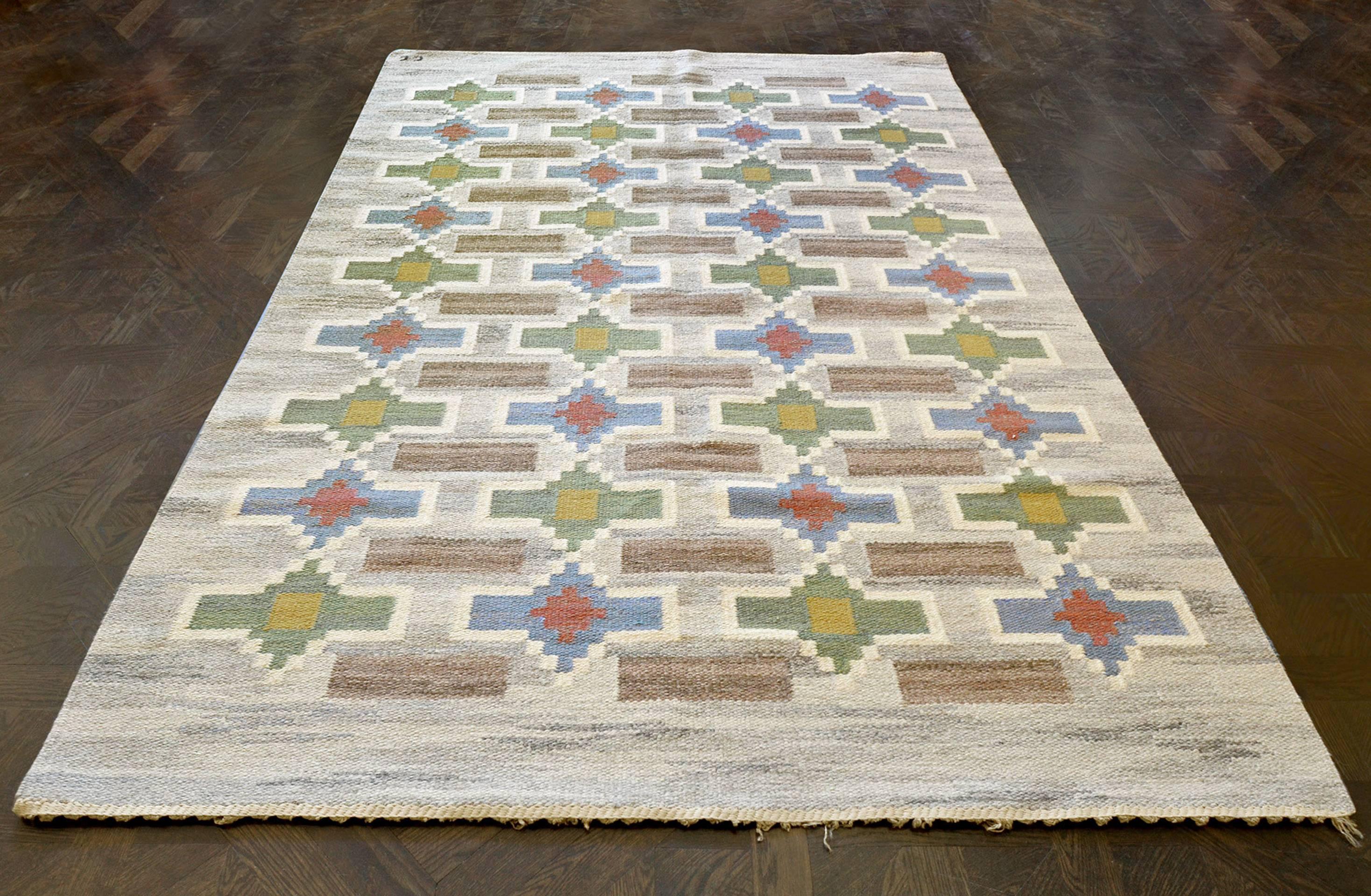 This vintage handwoven STRÖMMAR rug has a shaded grey overall field with elegant alternating stepped stylized cartouche lozenge lattice. The exceptional piece is signed by the master weaver, Judith Johansson Knäred, Sweden.