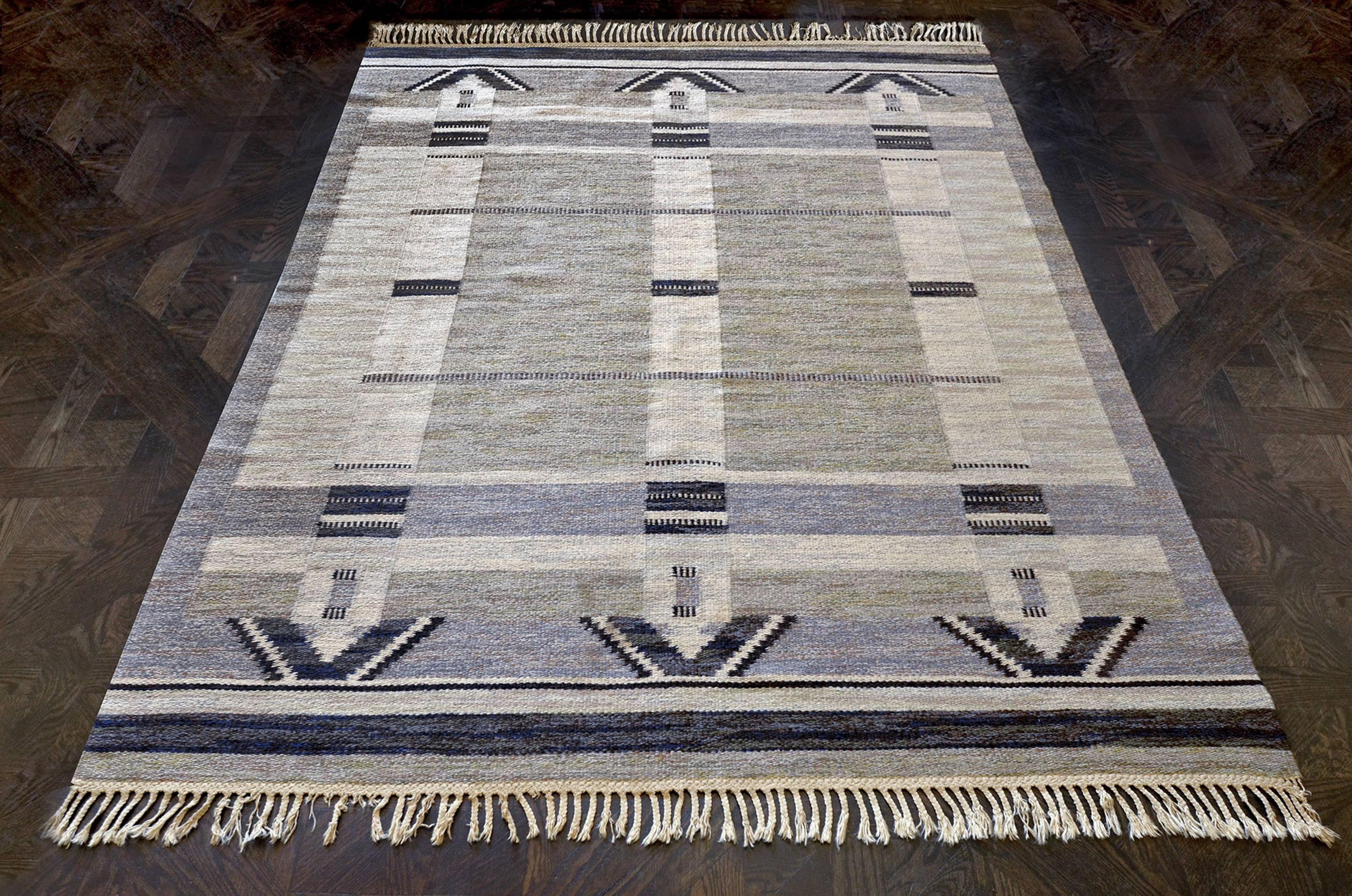 Ce tapis suédois vintage tissé à la main présente un champ gris sable interrompu par trois bandes ivoire avec des demi-lozanges en escalier anthracite à chaque extrémité, couronnées par des bandes anthracite et ivoire à chaque extrémité. Signé par