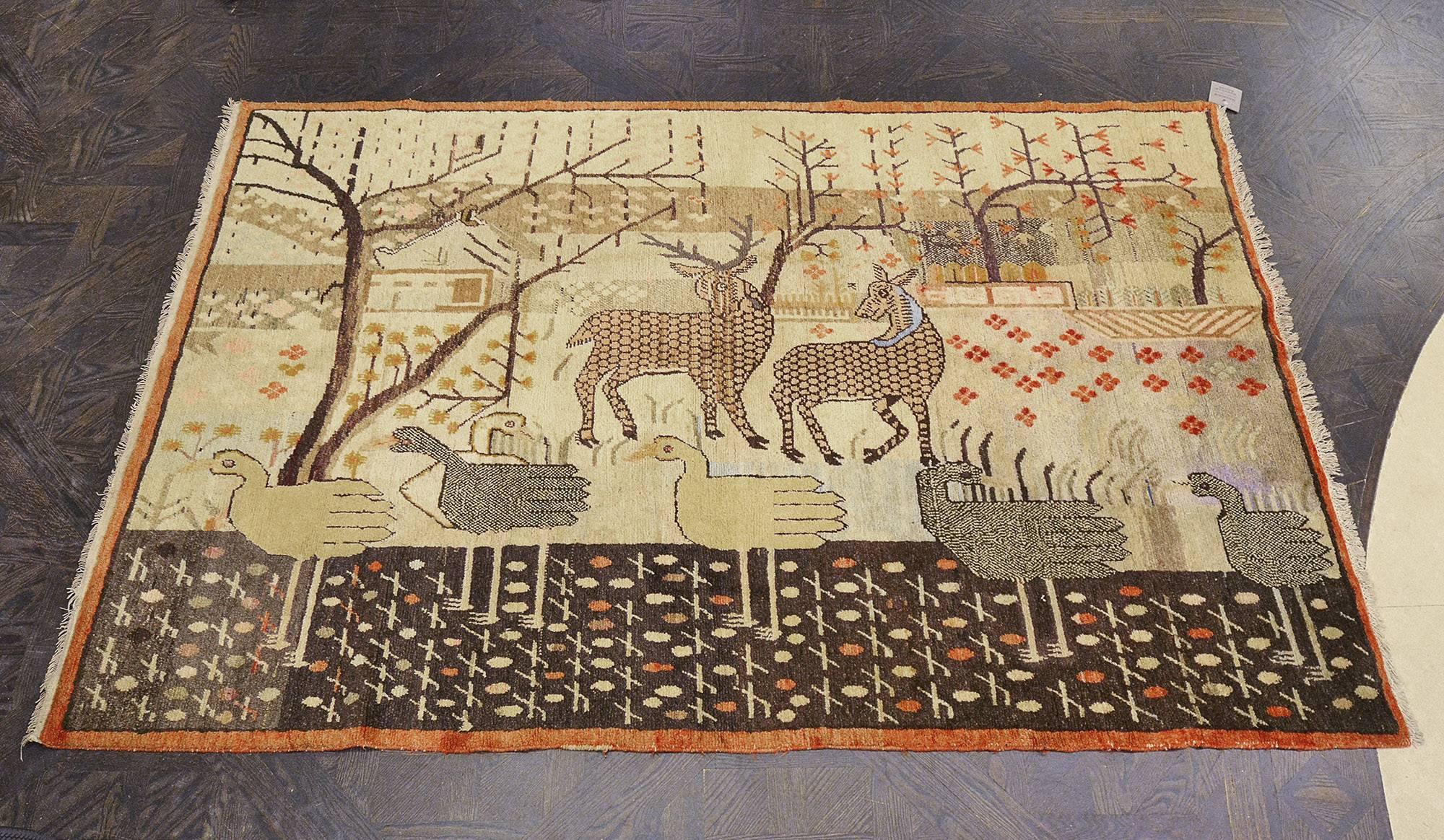 This traditional hand-woven Samarkand Khotan rug has an ivory pictorial field of geese and deer following in opposing directions, in a pasture of flowering trees, bushes, and bodies of water.