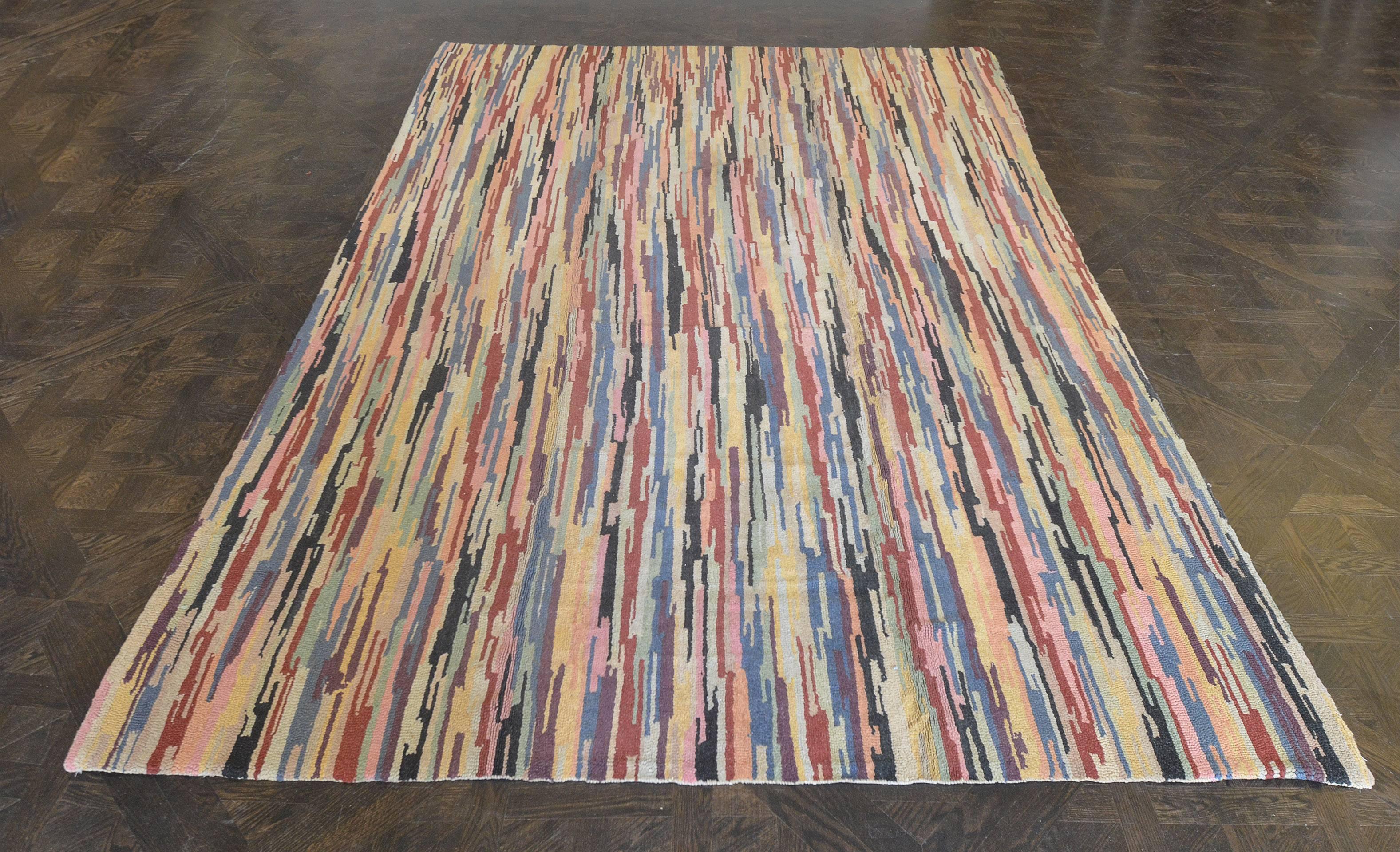 This vintage handwoven North American Hooked rug has an overall field of gently waving vertical polychrome strokes of green, blue, purple, pink, red and black, on a beige background.