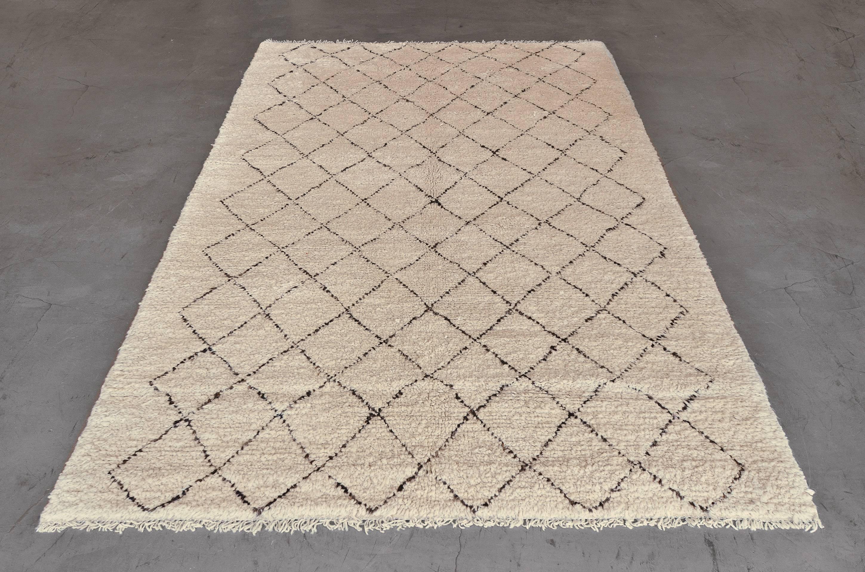 This vintage, 1970s, deep-pile, hand-woven Moroccan rug has an ivory field with a central panel of charcoal-black linked lozenges forming a lattice.