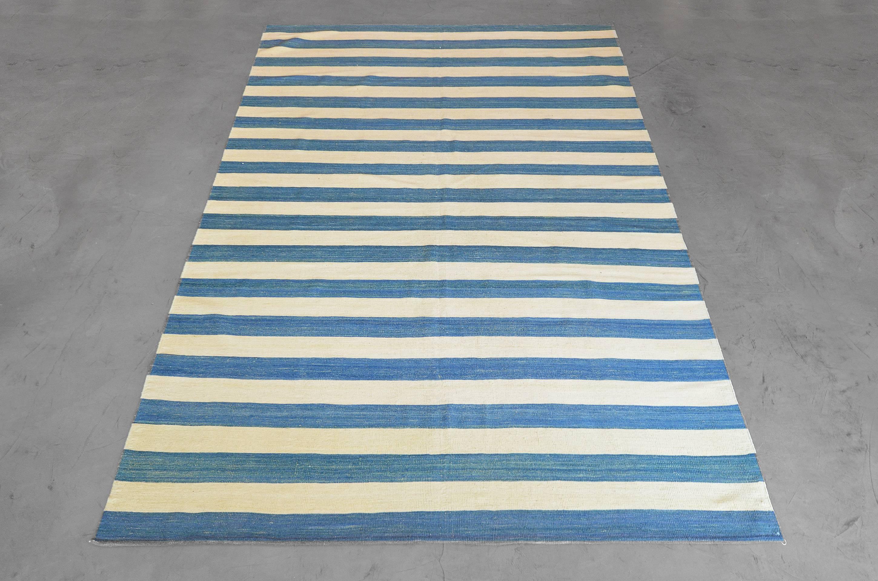 Indigo blue and natural wool form Classic stripes that create great foundations for transitional, costal, clean and modern rooms. The rug is nearly square at 6.3” x 6.9” and newly flat woven using the finest wool from Turkey.