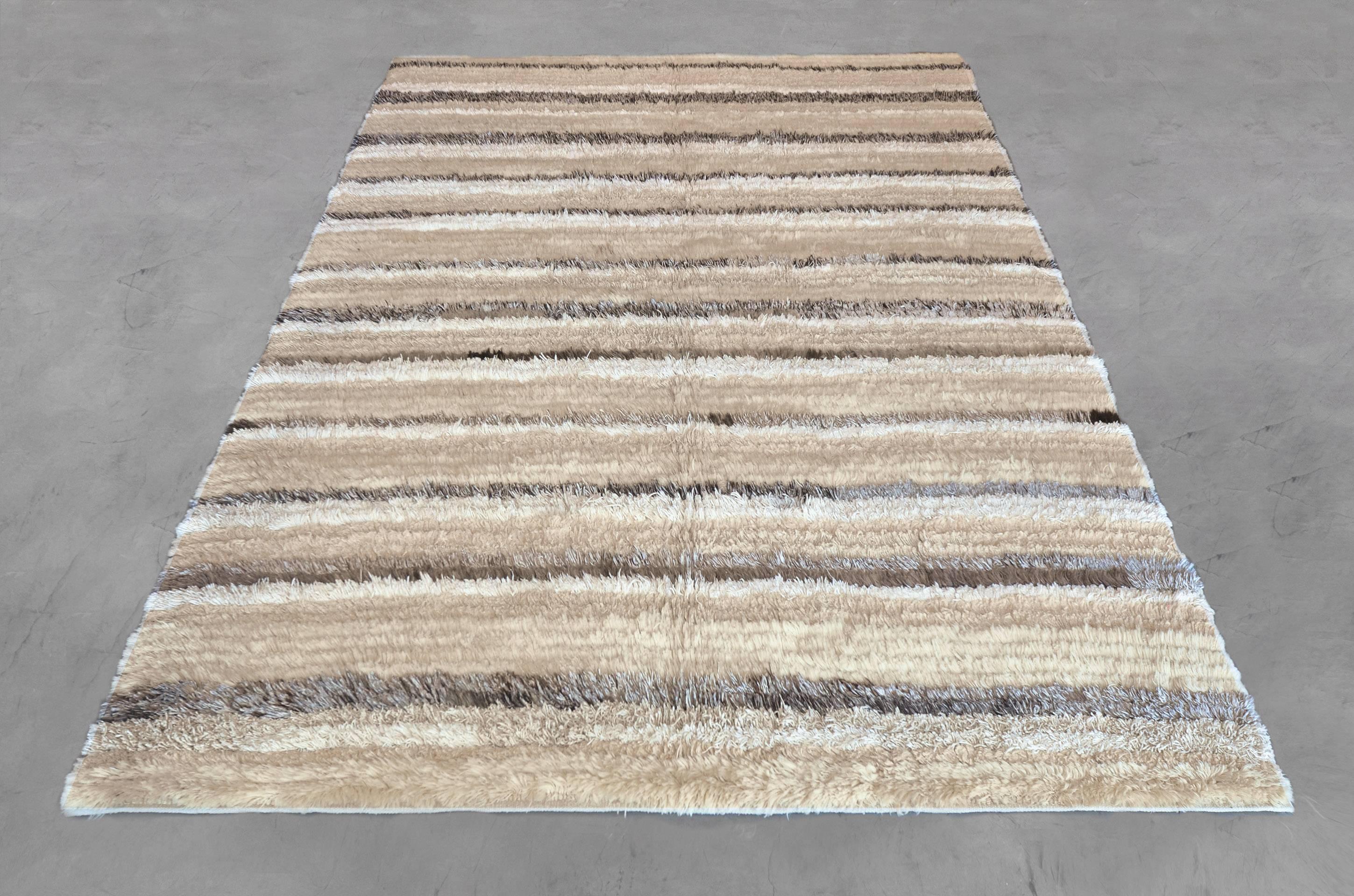 This exceptionally unique long pile rug from Turkey is hand-knotted from the finest wool, hemp, linen, and goat hair. The Minimalist inspired design of this rug is crafted by horizontally layering these complementing materials. Sized at 7’2” x 9’