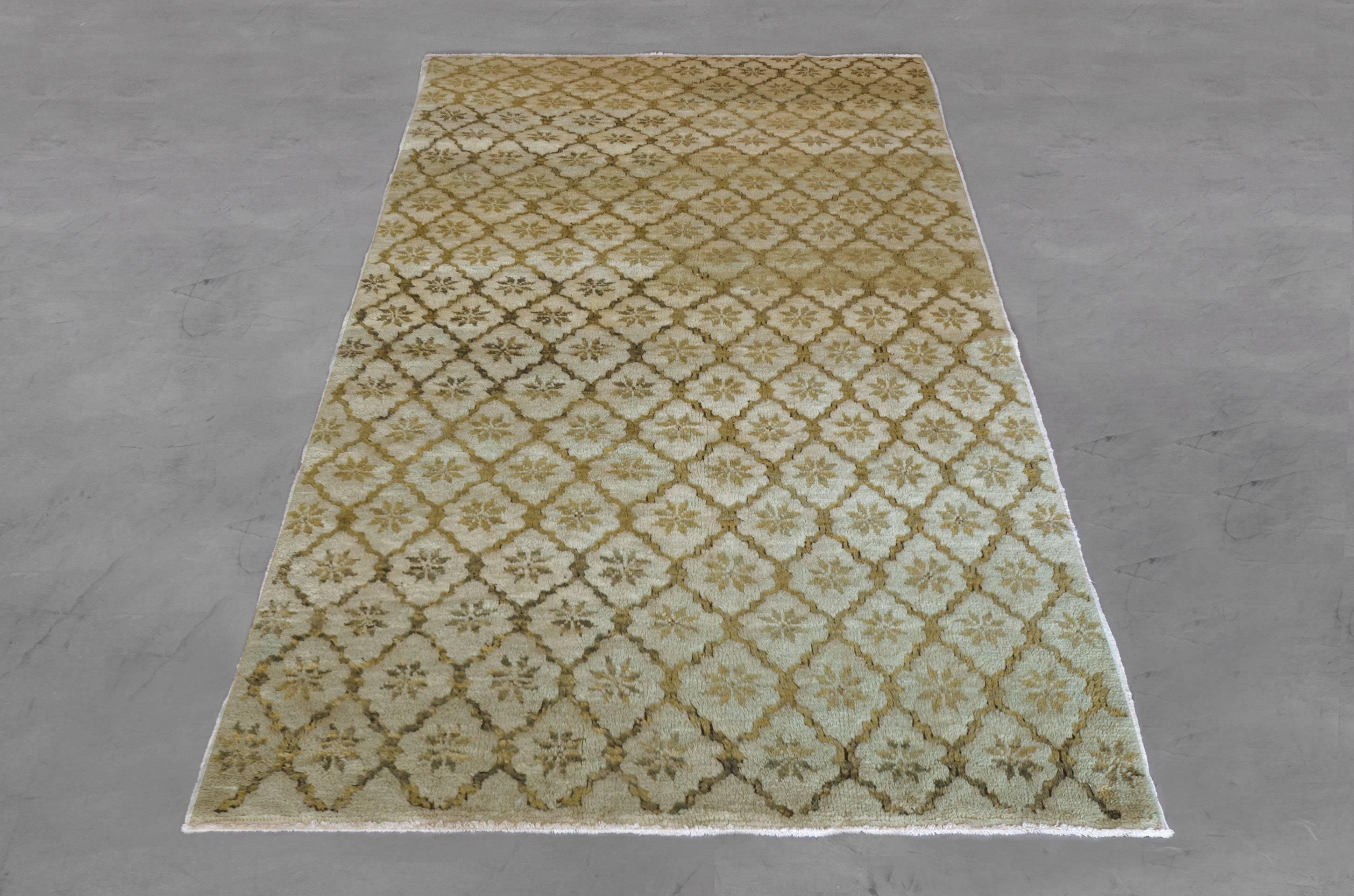 This hand-knotted, wool Turkish rug from the mid-20th century showcases a delicate all-over pattern in an understated palette of green earth tones. The delicate, modern rosette motif tessellates across the 5’ x 8’ soft pistachio green field