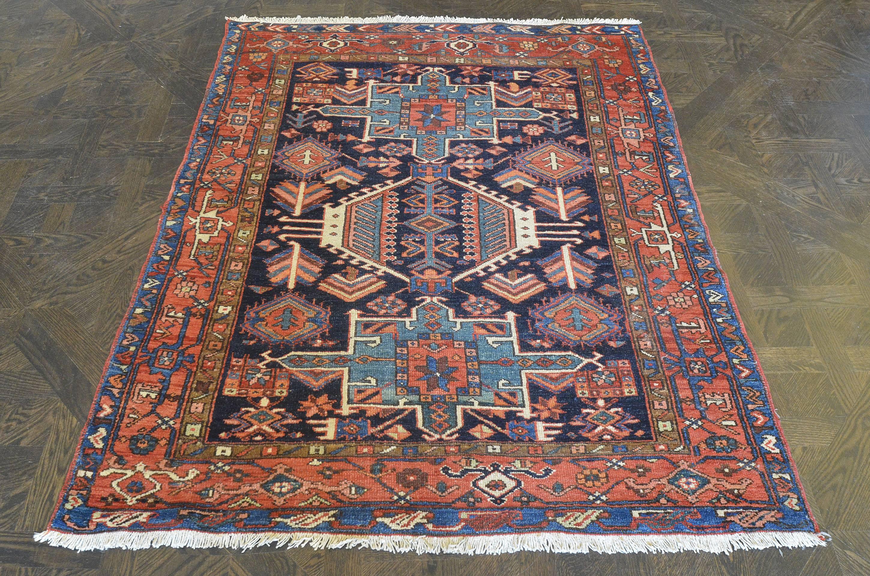 This traditional handwoven Persian Serapi rug has a deep indigo field of sparse tribal motif enclosing complementary geometric medallions, in a terracotta linked turtle palmette border, between stylized vine stripes.