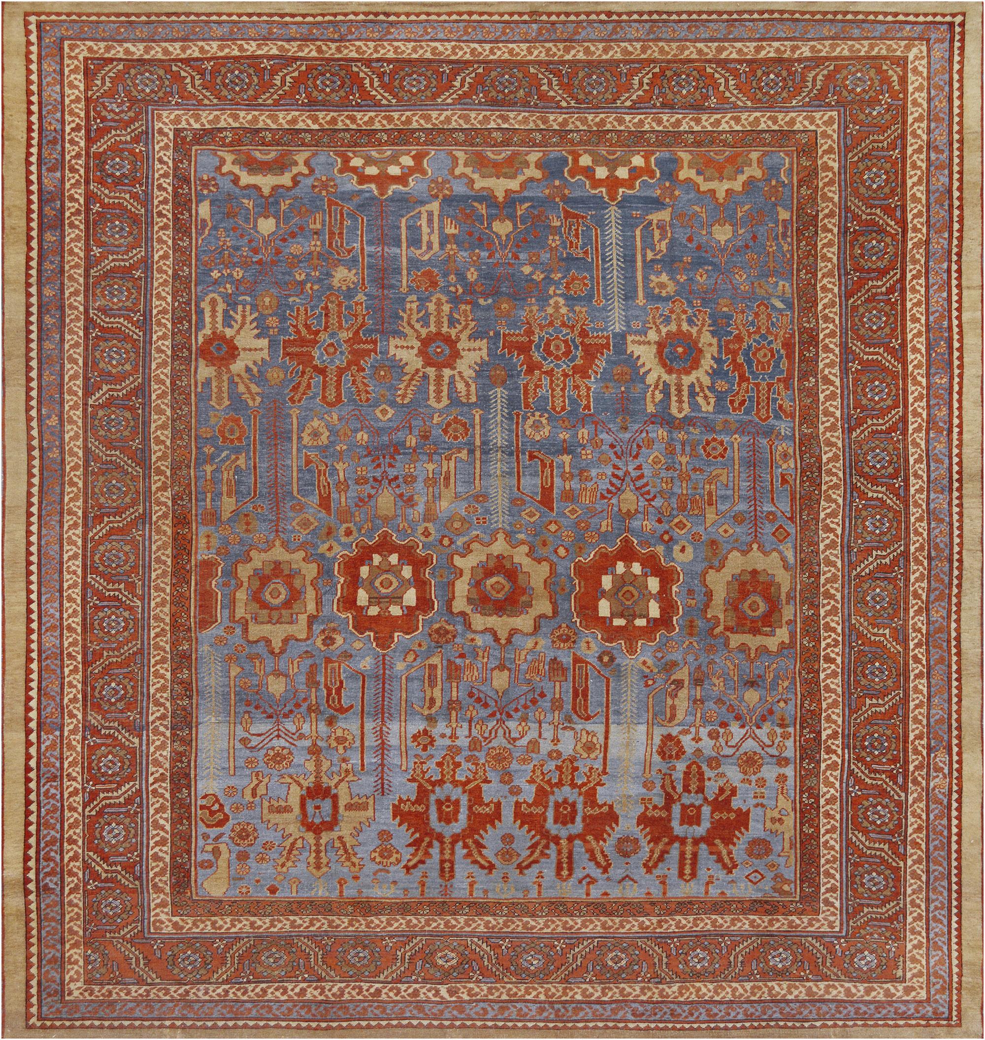 This traditional handwoven Persian Bakhshaish rug has a shaded ocean blue field counterposed by broad geometric palmettes issuing complementary floral motif, in a coral red border of scrolling geometric rosettes between a profusion of delicate vine