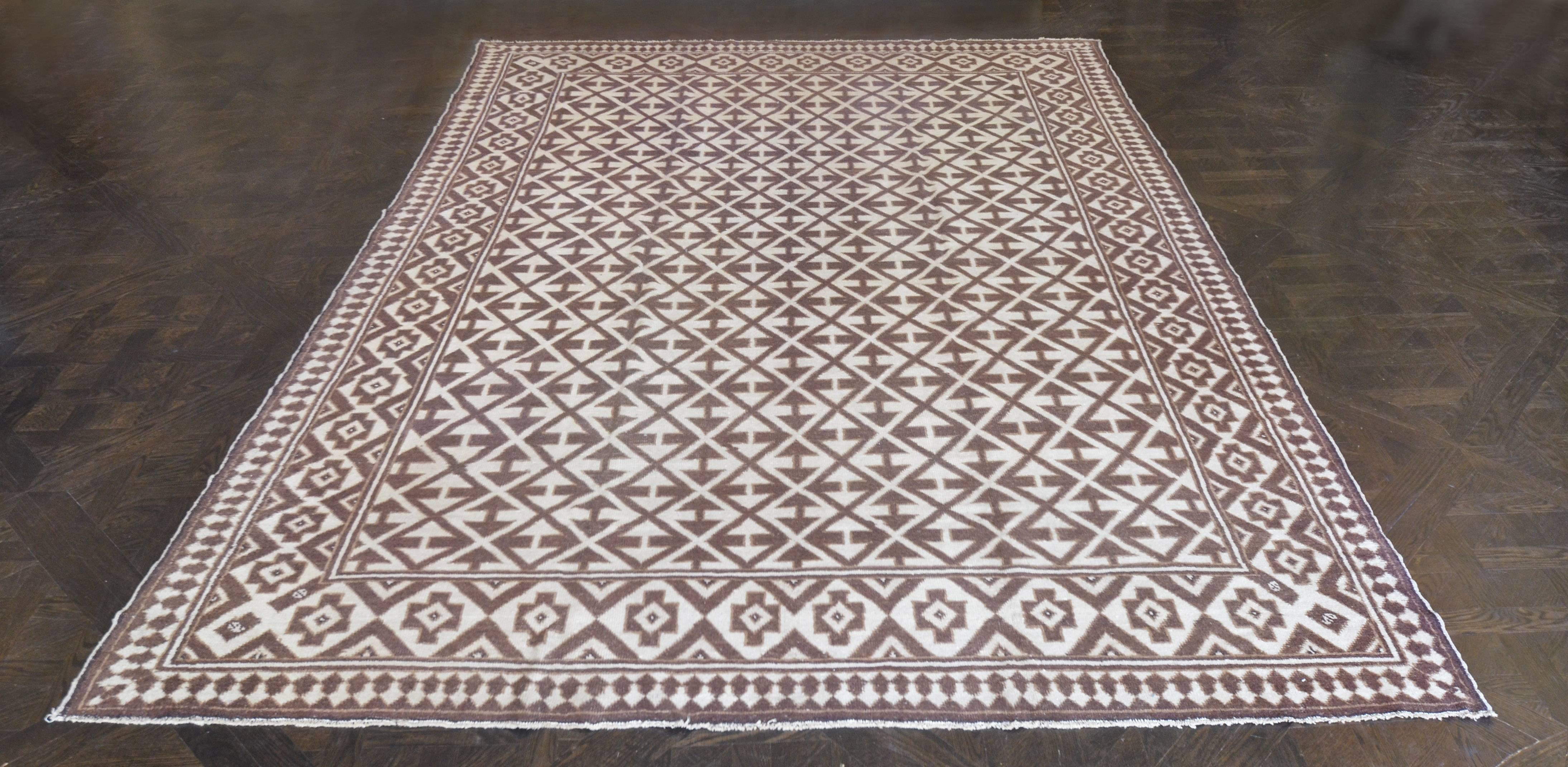 This traditional handwoven Moroccan rug has a chocolate field with diagonal lozenge lattice of reciprocal arrow motif, in an intricate steel and brown two-tone geometric border, outer reciprocal skittle-pattern stripe. 100% Wool.