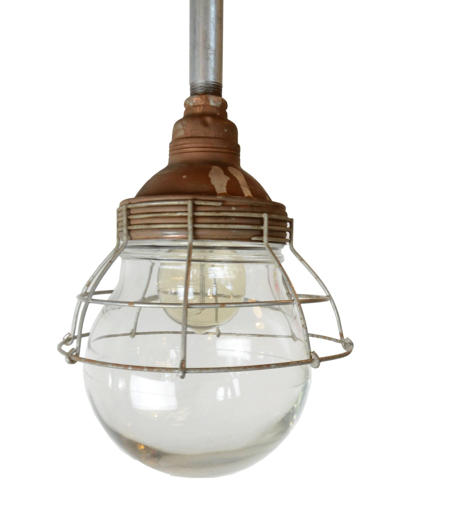 Unique Industrial copper pendant from the Benjamin Electric Manufacturing Company. It features a large, round glass shade and caged overlay. Available in two variants: tall and short. 

Finish: Original
One medium socket
Measures: Short: 19