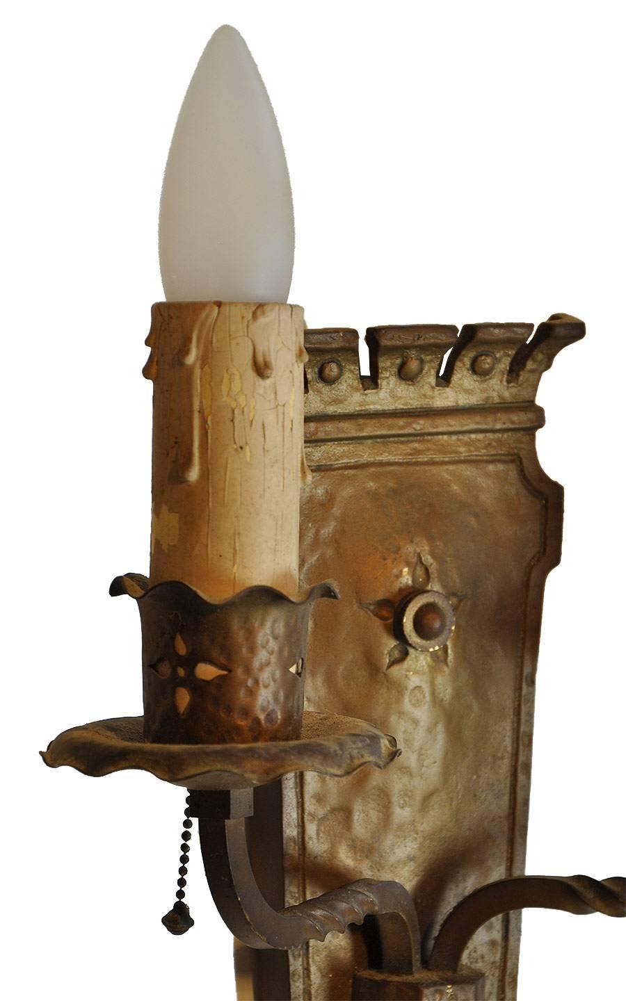 Hammered bronze interior two-candle sconce with twisted metal detailing throughout and decorative cut-out floral designs on the candle holders.
We have two available for purchase.

We find that early antique lighting was designed as objects of
