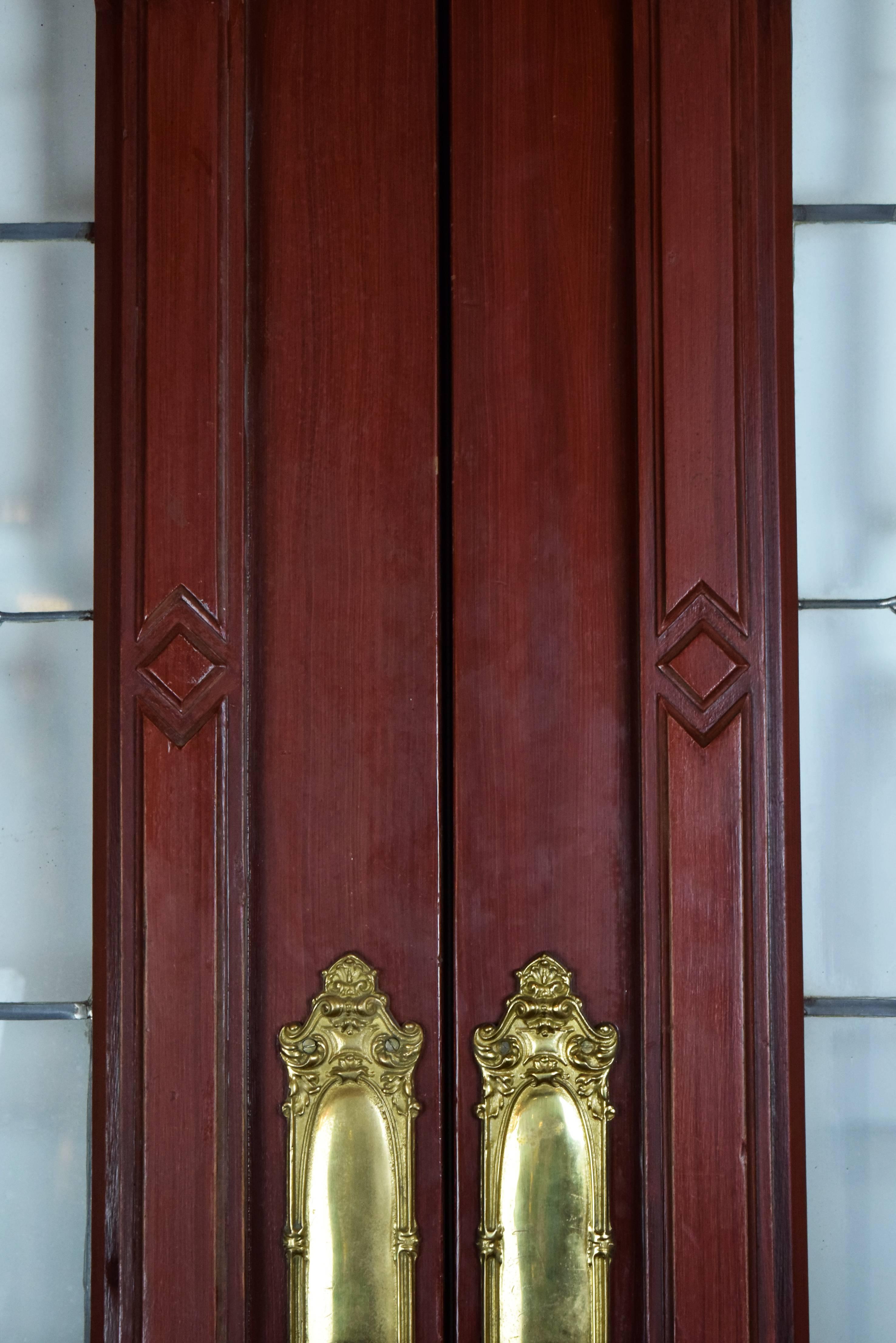 This entrance door set has beautiful beveled glass windows bordered by patterned woodwork, two beautiful, elaborate cast brass door plates reproduced especially for these doors and beautifully designed woodwork throughout. These doors would be a