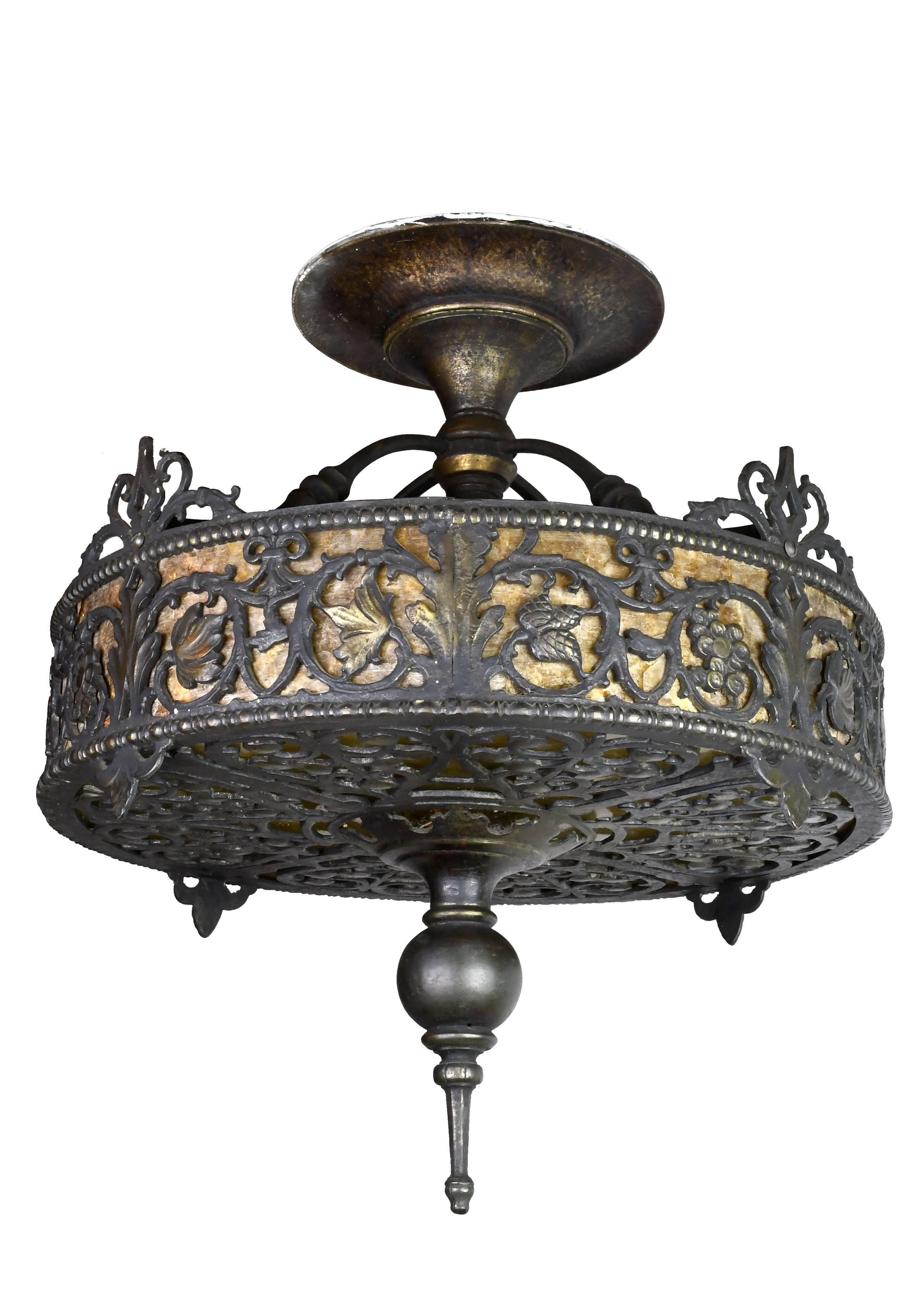 Attributed to craftsman Oscar Bach, one of the most skilled and stylistically diverse metalworkers of the early 20th century, this incredible flush mount chandelier is alive with intricate details. Bronze metalwork weaves its way over rich mica
