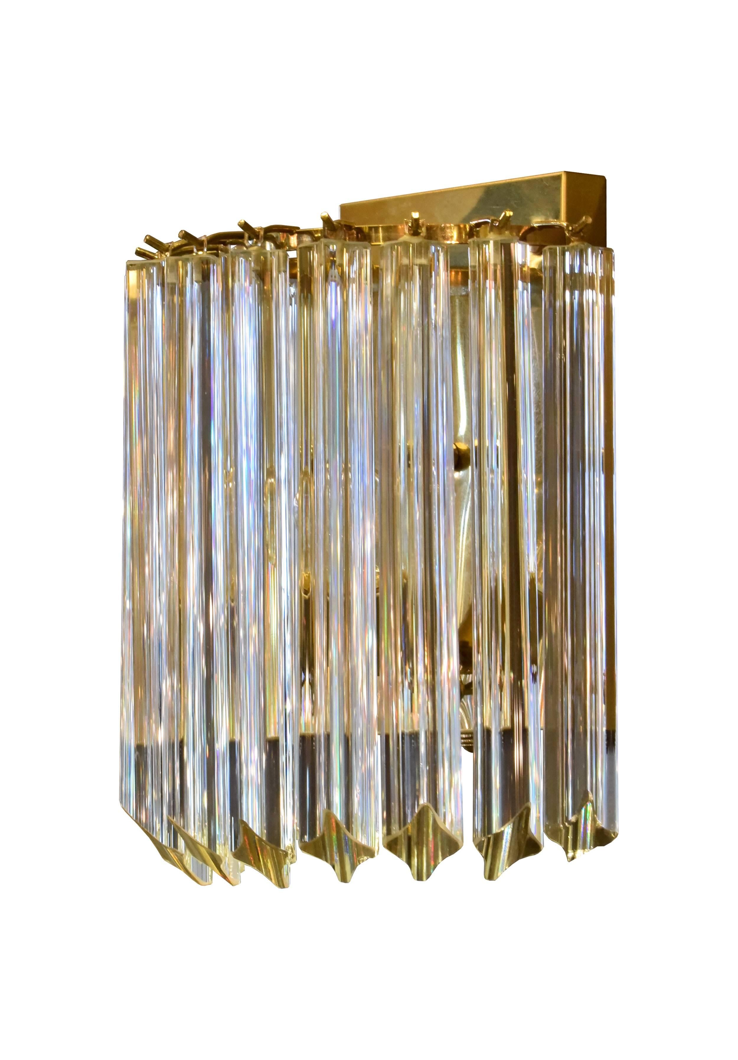 Long, hanging Triedri crystals drape luxuriously from the shiny brass back plate of this Venini sconce. The crystals are weighty and exceptionally crafted, and they reflect the warm, rich tones of the interior light when illuminated. Two available, 