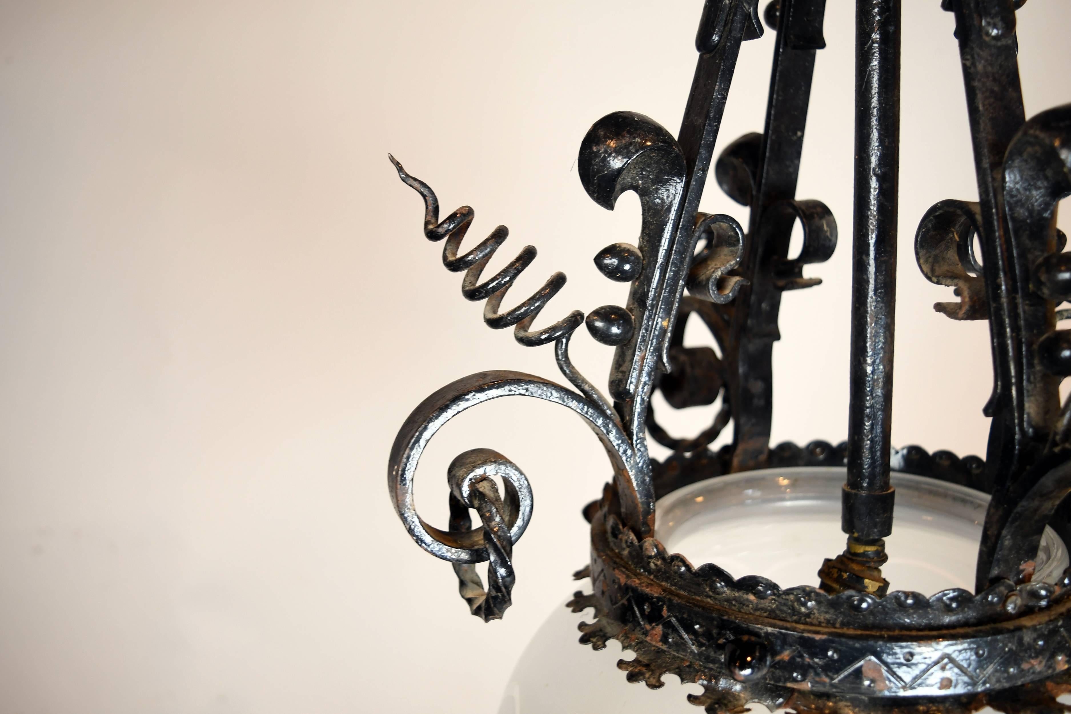 This beautiful iron pendant is adorned with unique Victorian style decorations. The leaf shaped canopy and the spiral corkscrew embellishments are highly decorative and visually stunning. The glass shade is semi-transparent with repeating, circular