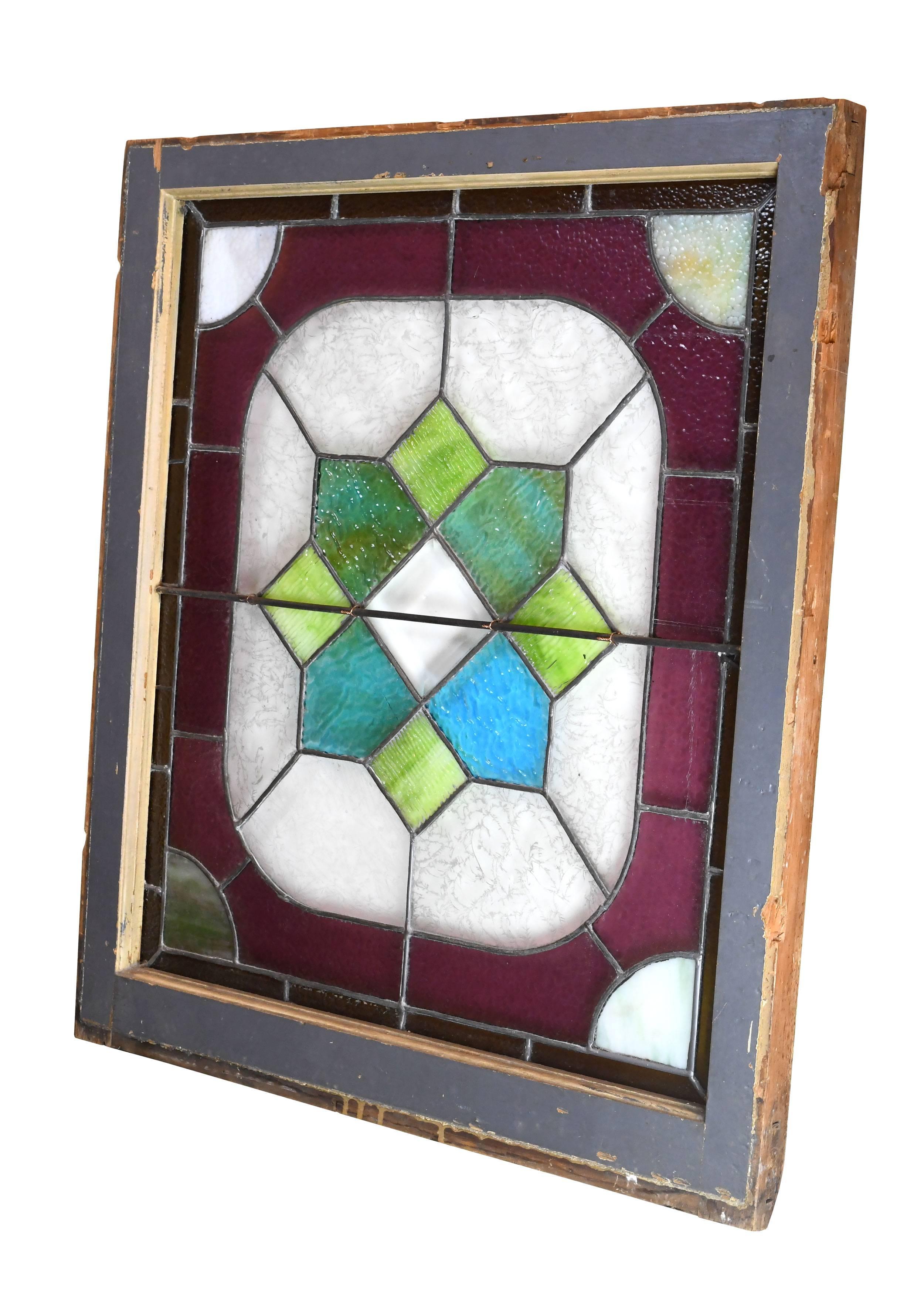 The bright, jewel-like colors of this Victorian stained glass window will brighten up any space in a pinch. Green and blue shapes surround a beautiful beveled diamond at the center, while magenta and orange glass forms a rich border that contrasts