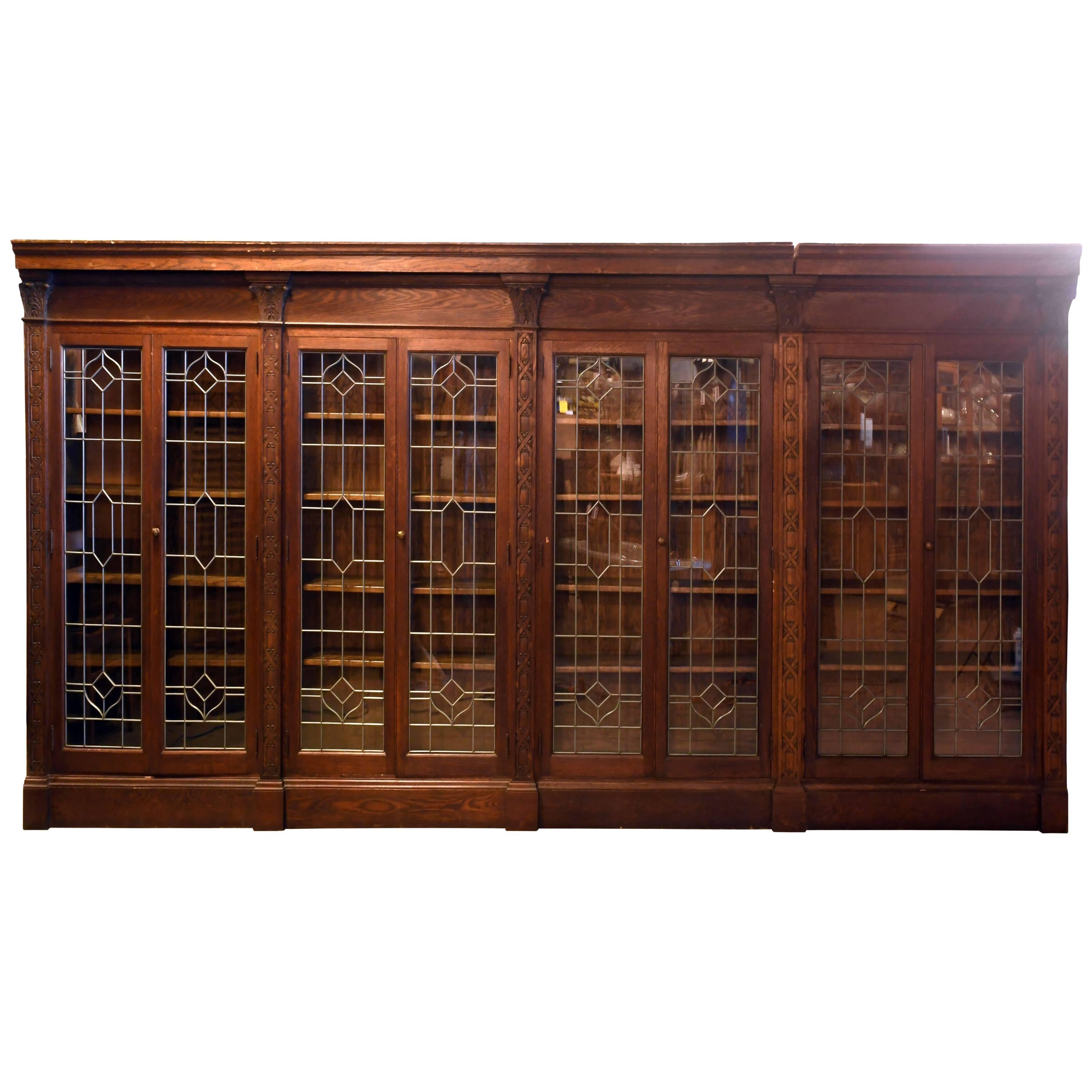 Cette longue bibliothèque en chêne est équipée de quatre ensembles de portes doubles en verre plombé qui contiennent chacune quatre étagères à hauteur réglable. Les boiseries regorgent de détails ; des clochettes mélangées à des losanges tissés sont