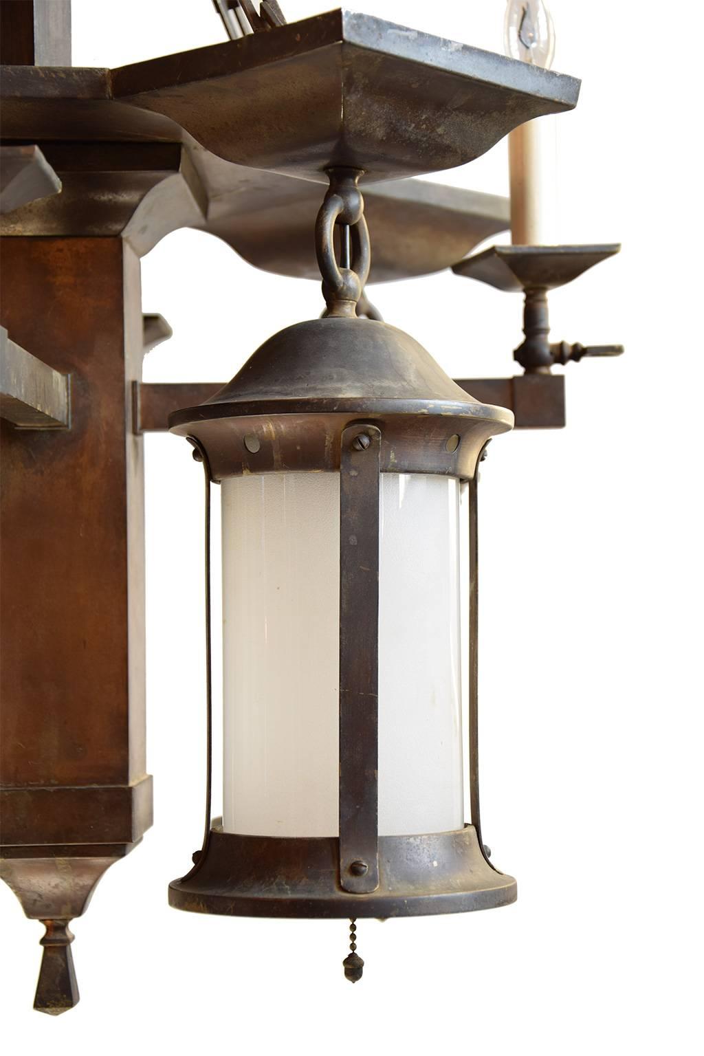 This handsome fixture creates an authentic turn-of-the-century feel that only a gas/electric chandelier can provide. It features original brass parts, square chain, patina and glass. Gas lights were most commonly used between 1820-1920, gas or