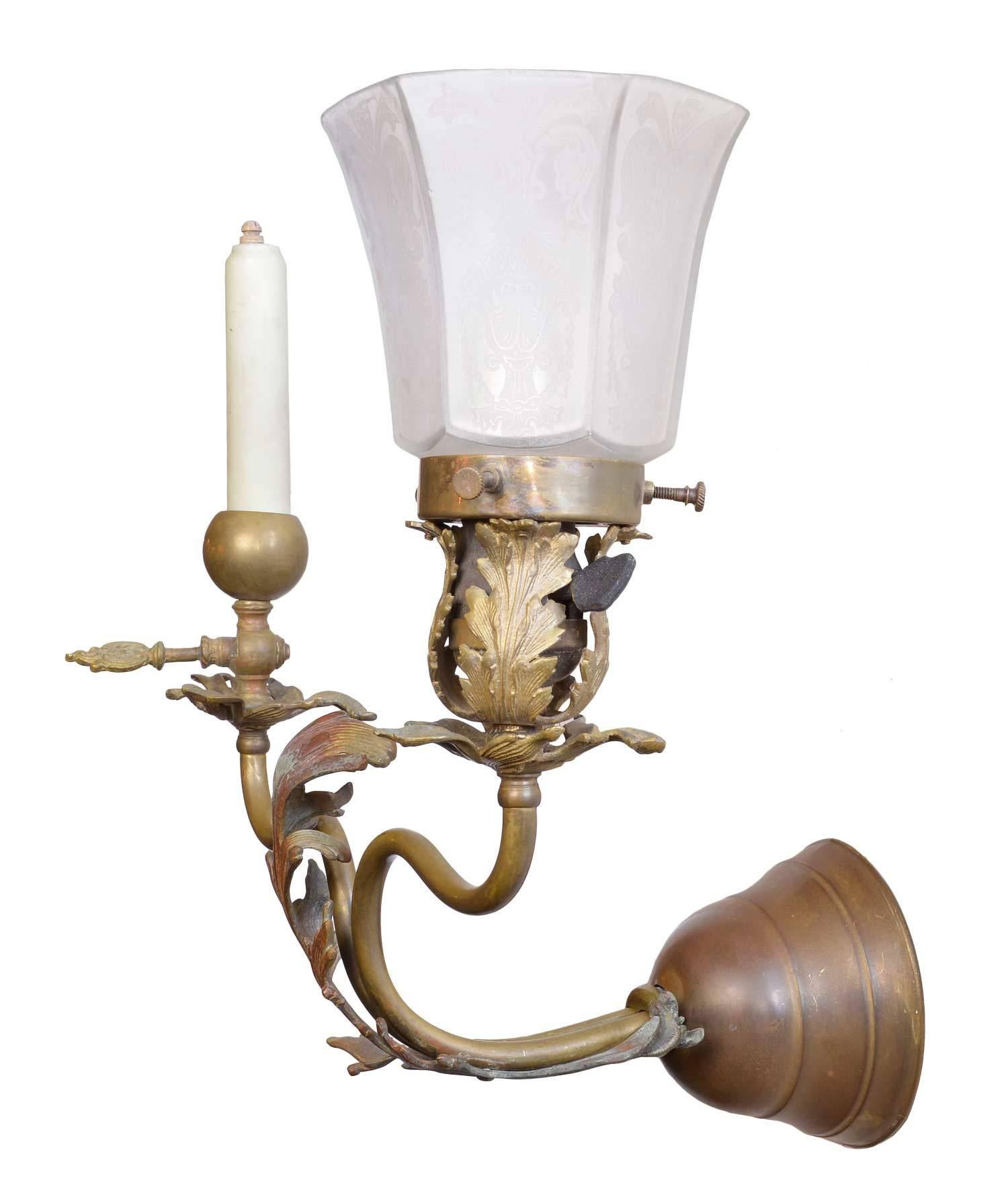 Cast leaves adorn this smart looking sconce from the turn of the century. The fixture is completely original with etched glass shade, glass candle cover, cast leaf details, rich brass patina, Hubbell socket and ornate gas key. 

We find that early
