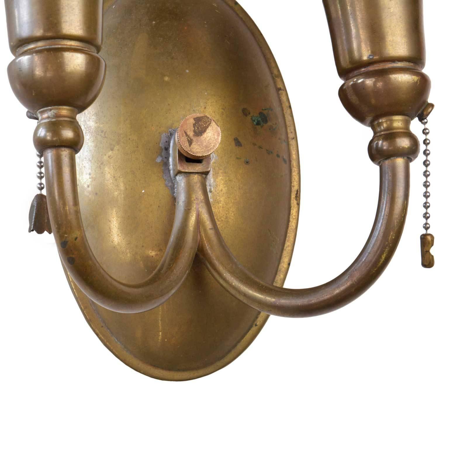 Handsome and simple signed Bradley and Hubbard brass sconce suite that includes one two-arm sconce and two single candle sconces. The heavy cast brass still has its original patina and pull chains. Signed B & H on the back of each fixture. All three