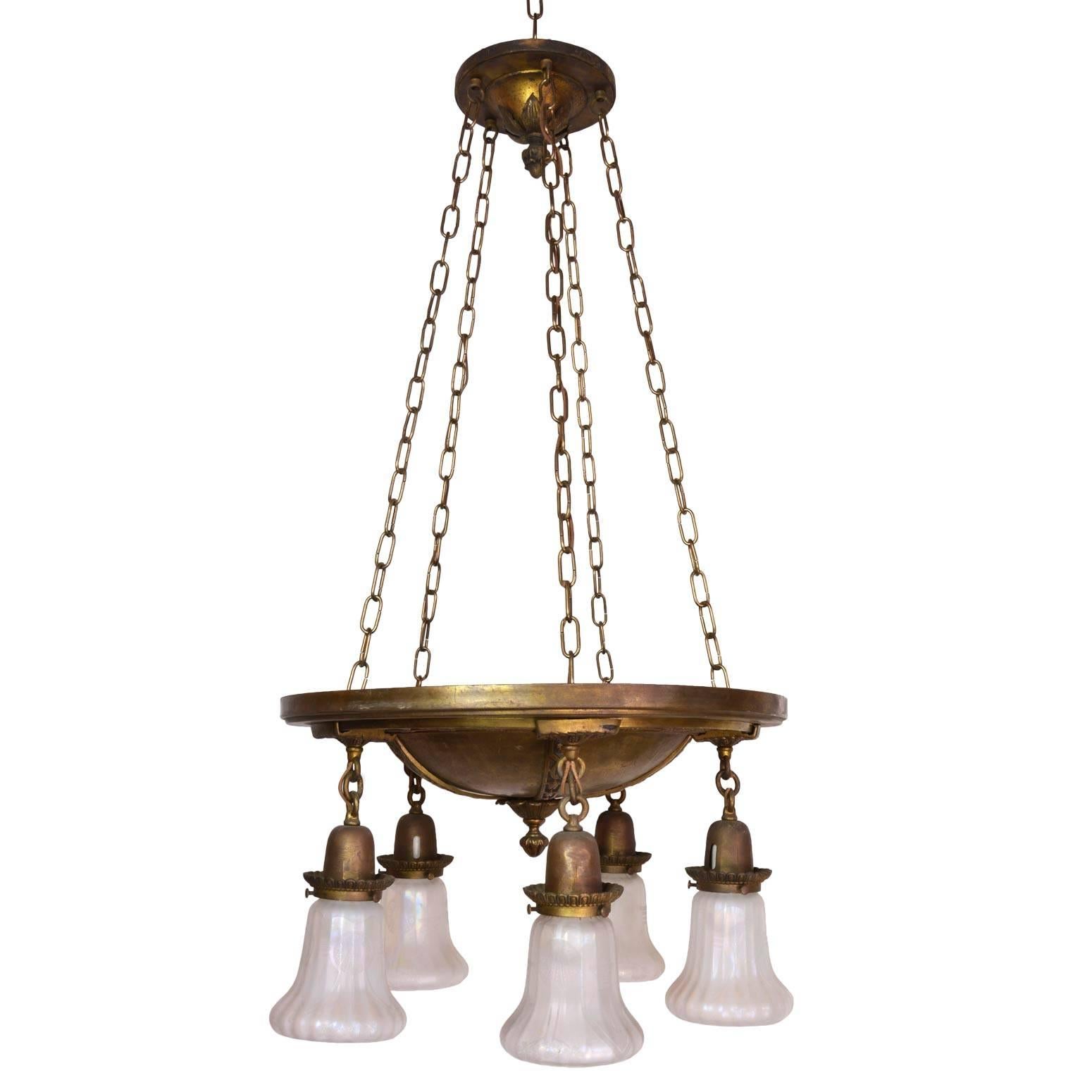 This lovely fixture is a great size for many rooms. It includes American Classical-style ornamentation in the brass  original shades, attributed to Steuben. When lit, the fixture reflects light from the rich brass patina, casting a warm glow over a