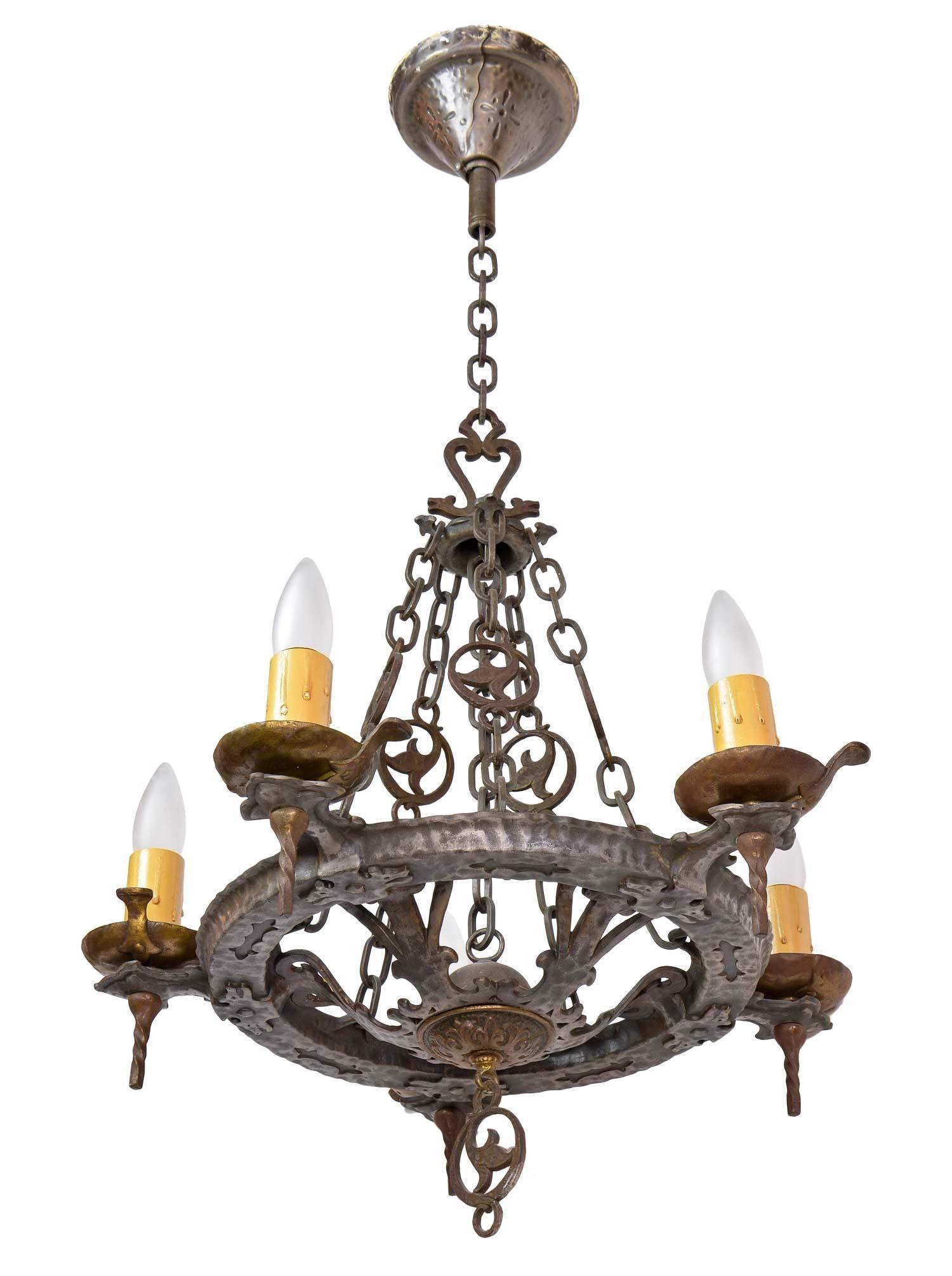 This iron chandelier is plated in brass and pewter and includes a great decorative chain, original canopy and Gothic details throughout, in keeping with the Tudor Revival style popular around the time of this fixture's making. 

We find that early