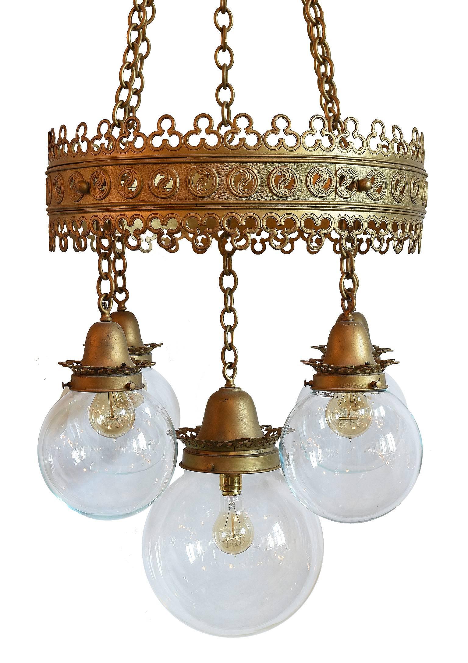 This beautiful brass chandelier made circa 1905 features trefoils and other Gothic detailing along with its wonderful original glass and canopies. Great construction and design and matching pair available. 

We find that early antique lighting was