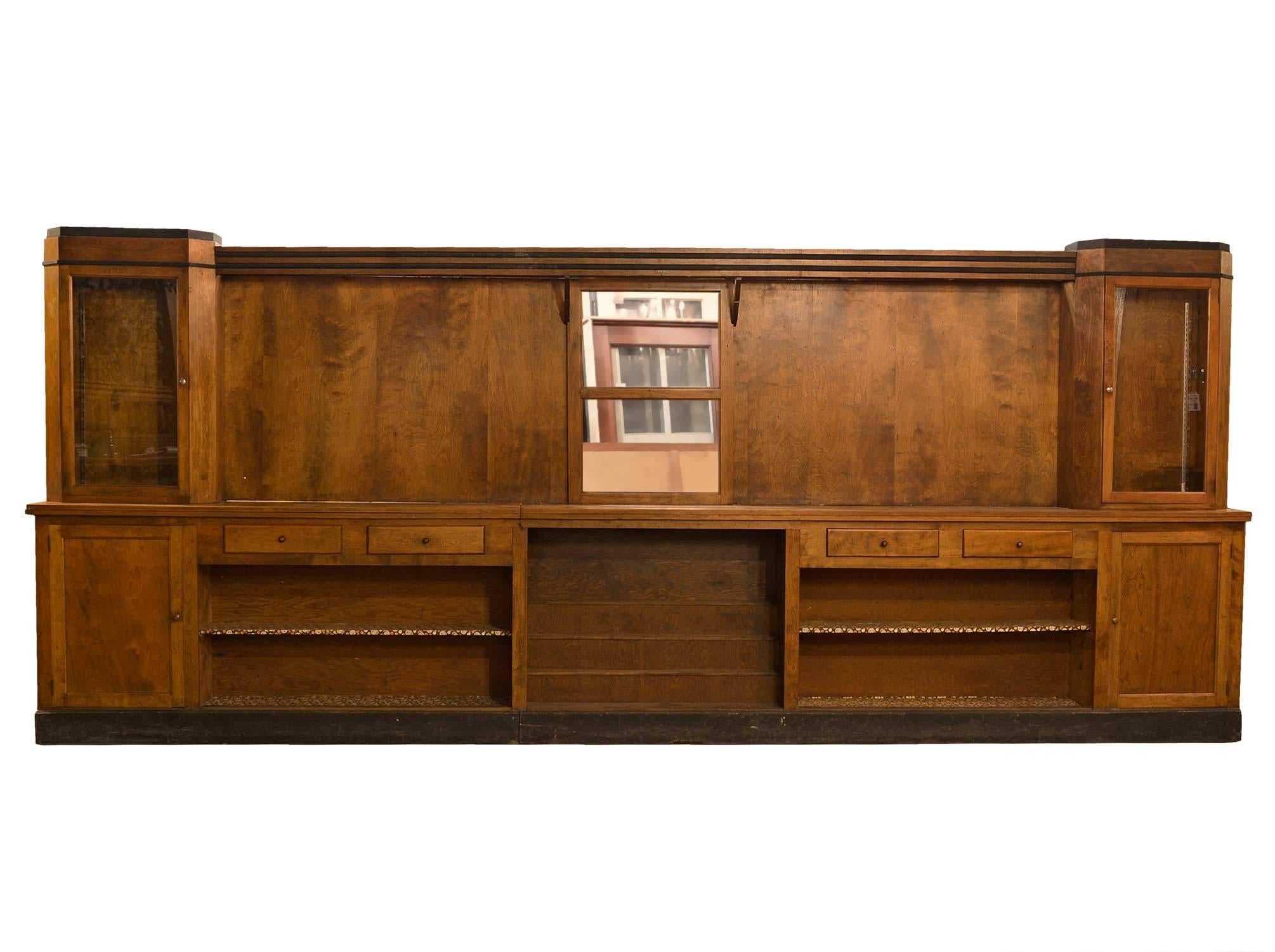 A simplistic Art Deco Brunswick back bar and counter with glass door upper cabinets, lower cupboards, shelf, and multiple drawers.  

Back bar: 216.5" long x 18.25" deep x 92" tall.
Counter: 264.25" long x 21.75" deep x
