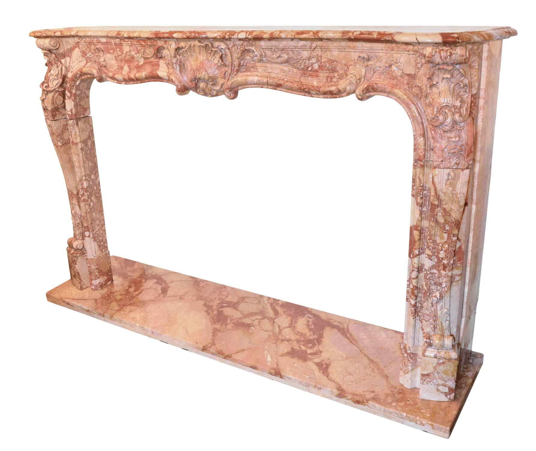This mantel is made of red marble and features a shell keystone with decorative leafy details across the front and legs. Original hearth included.