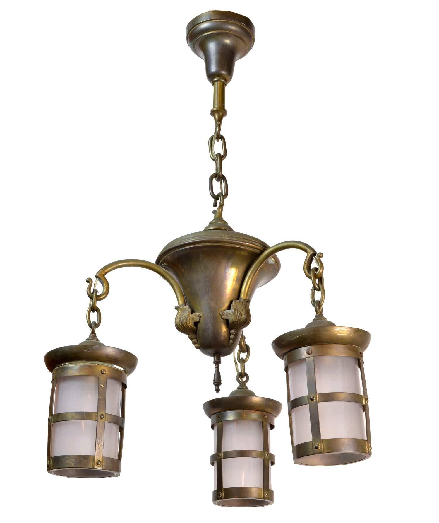 This chandelier is a unique example of craftsman lighting. Elegant curved arms hold three lantern style shades with original etched glass and a perfect brass patina.

We find that early antique lighting was designed as objects of art and we treat