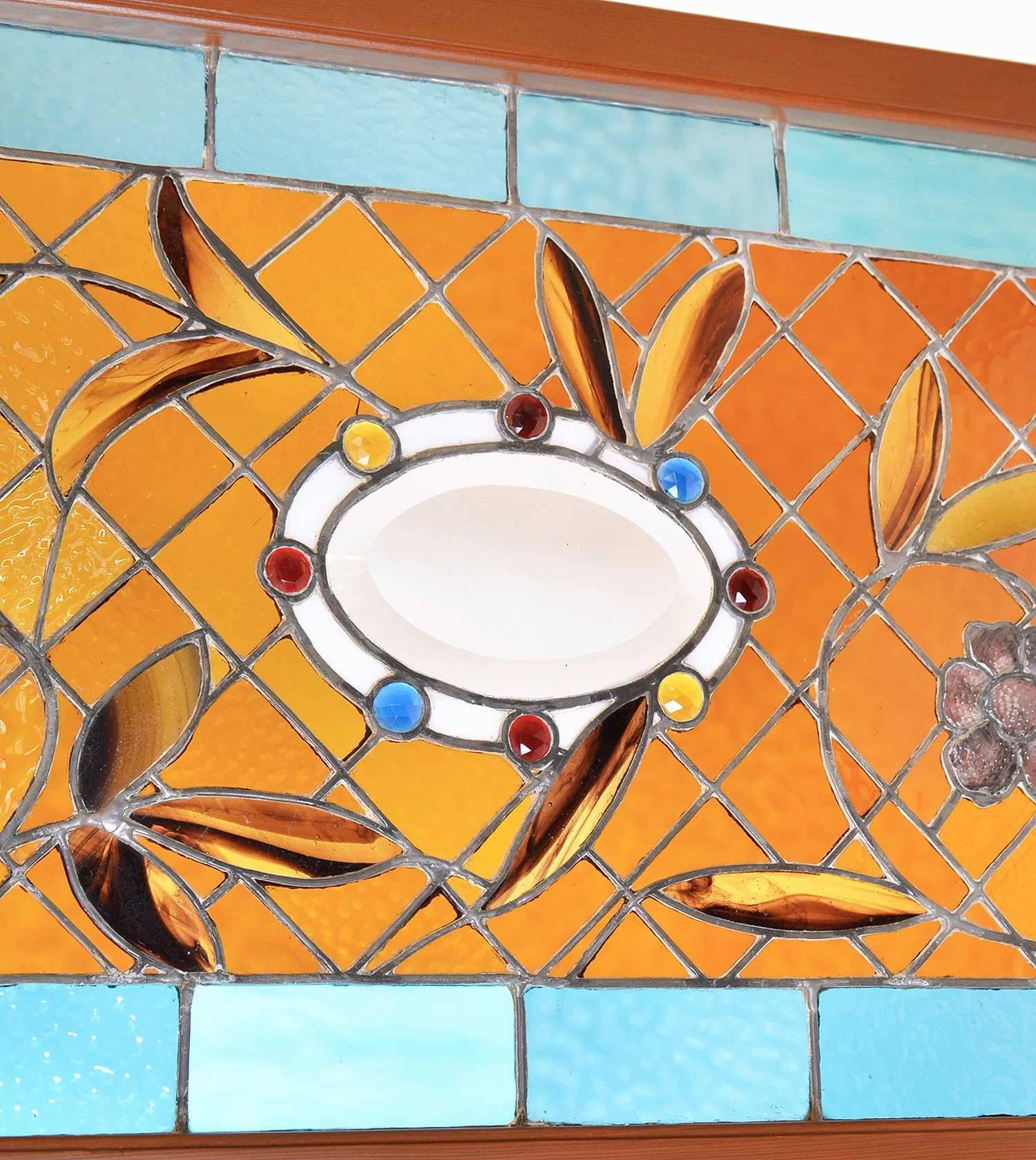 This Victorian stained glass window is a wonderful example of a stained glass artist's experimentation with color, design and texture. A beveled oval center surrounded by eight faceted round red, yellow and blue jewels create the focal point while