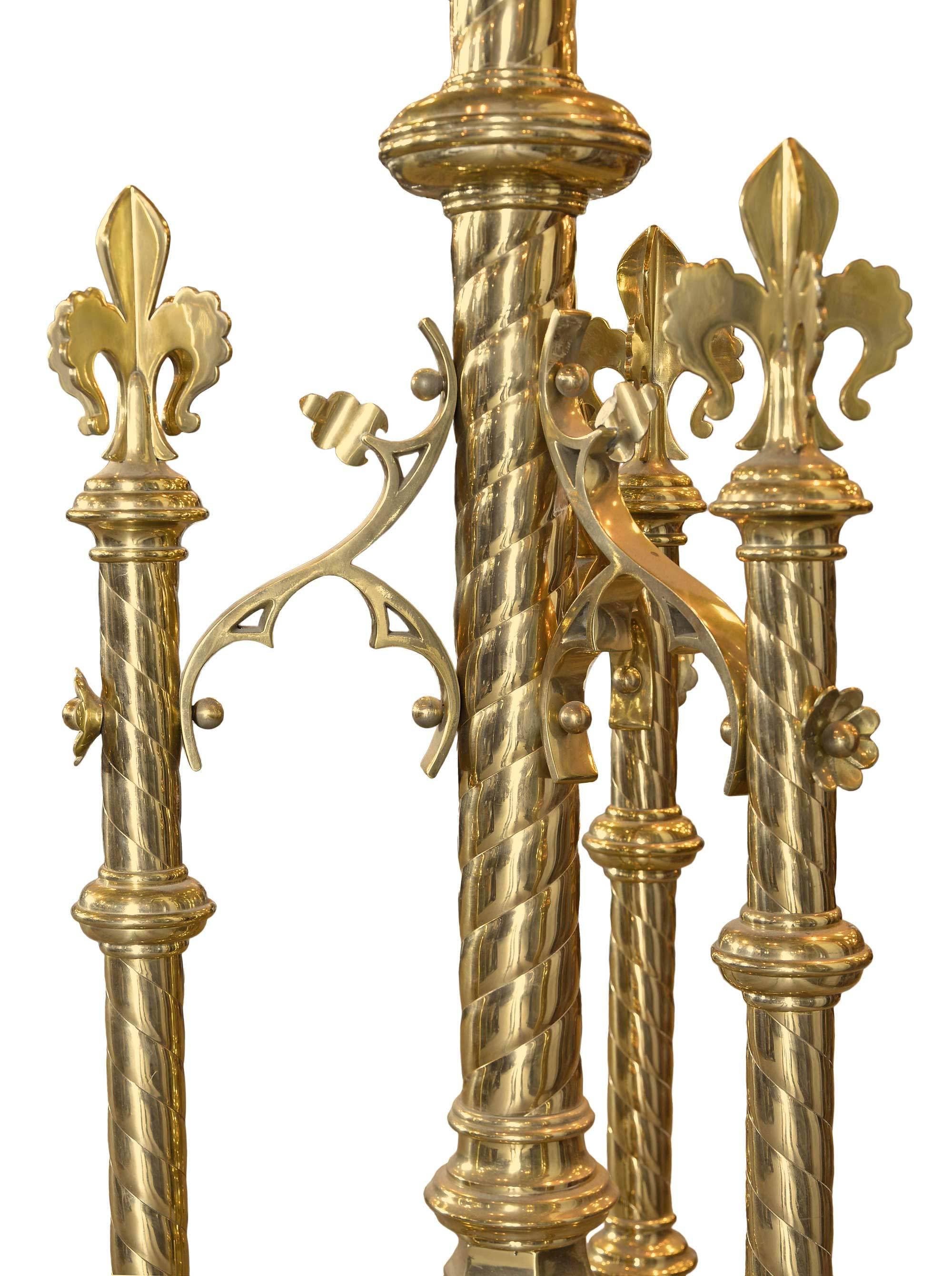 Ornate brass lectern with stylized three-dimensional fleur-de-lis, quatrefoil cut-outs with crosses, and twisted rods and scroll details, featuring engraved Christogram and inscription.