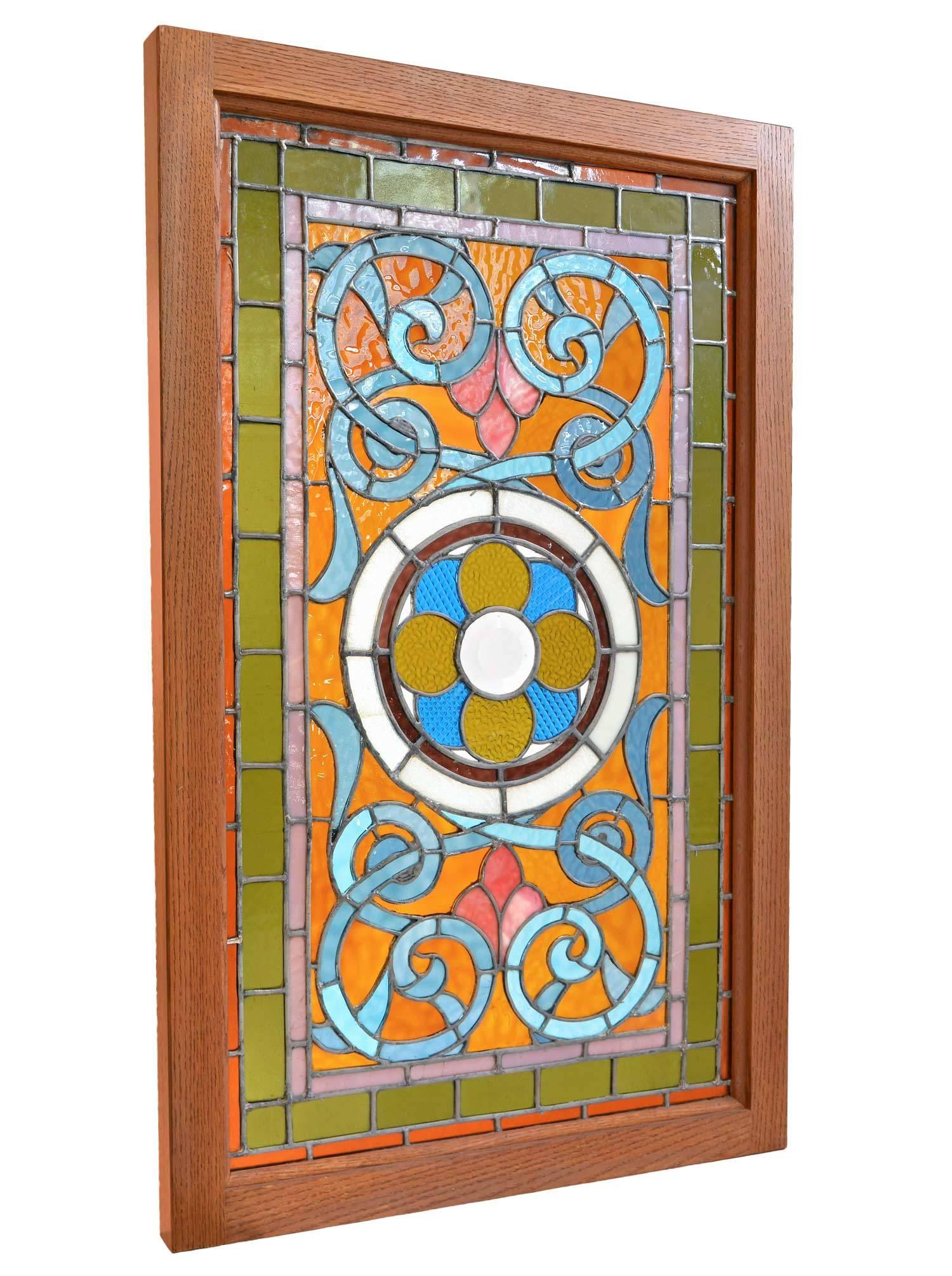 This beautiful Victorian stained glass window features amber and teal blue glass, and has a lovely pattern that centers on a large beveled rondelle in the center. The colors are bright, cheerful, and extremely vibrant.
