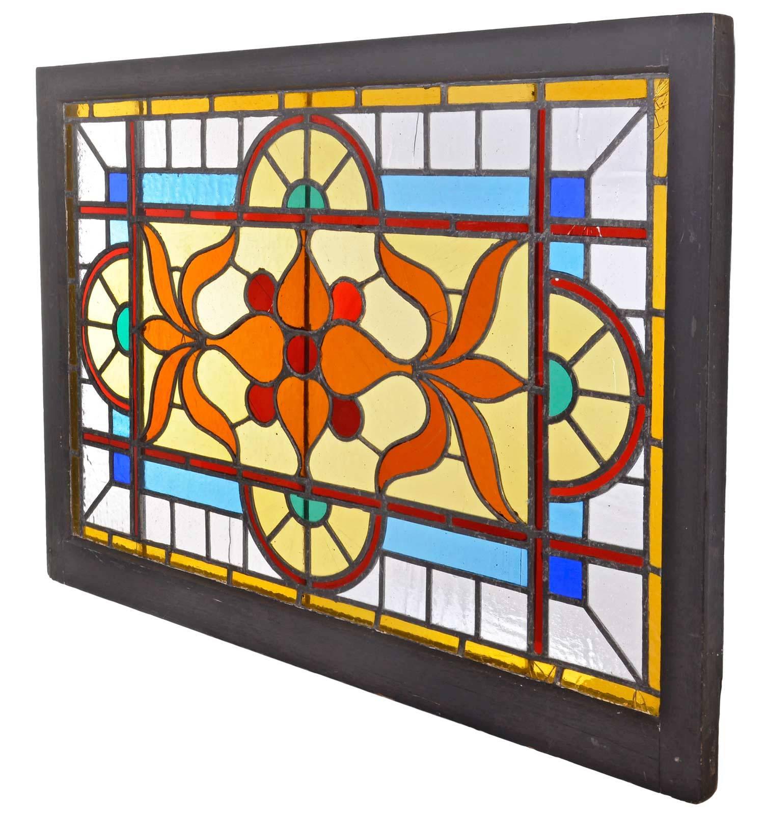 This vibrantly colored stained and flash glass window has an orange stylized Victorian floral motif at its center with geometric accents surrounding it. Made circa 1895, this antique piece is an ode to the past, yet perfect for bringing color to any