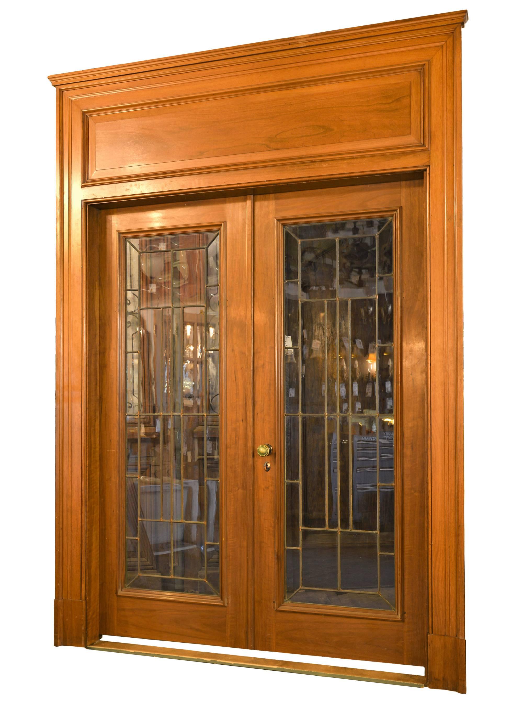 Meticulously removed from a 1915 home in Hinsdale, Illinois, this fantastic French door unit is made from beautiful walnut and leaded glass. These doors are complete with their original cast brass hardware and over-sized walnut panel trim and jamb.