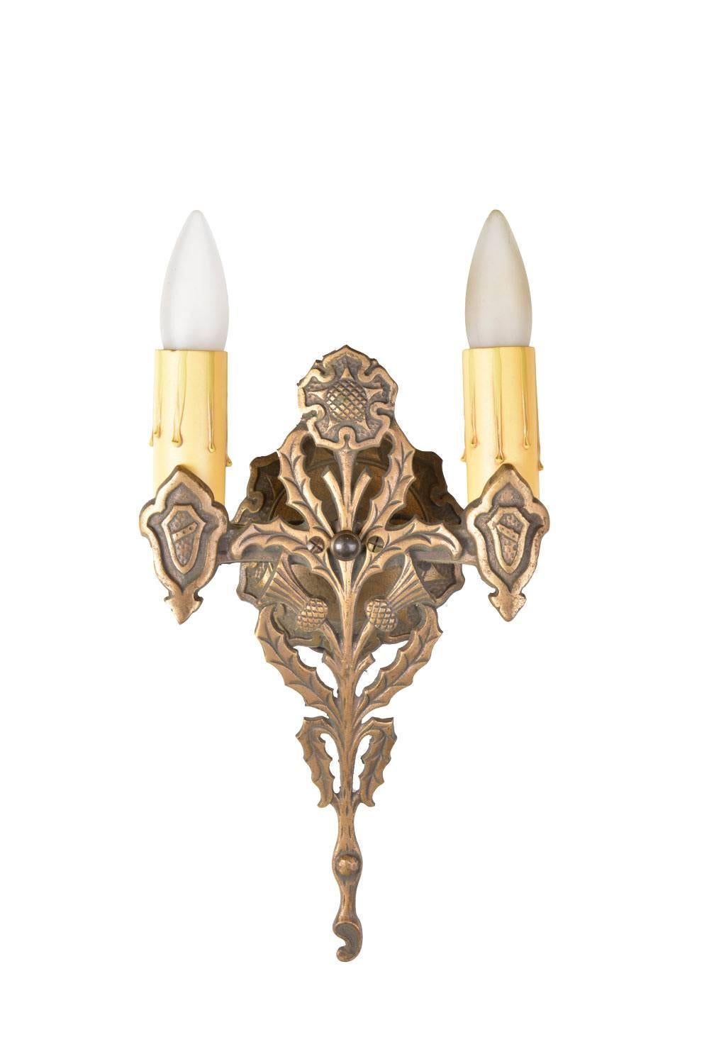 Beautiful and rich in tone, this two-arm bronze thistle sconce was designed in the Gothic style, with ornate leaf and flower detailing. 

We find that early antique lighting was designed as objects of art and we treat each fixture with careful