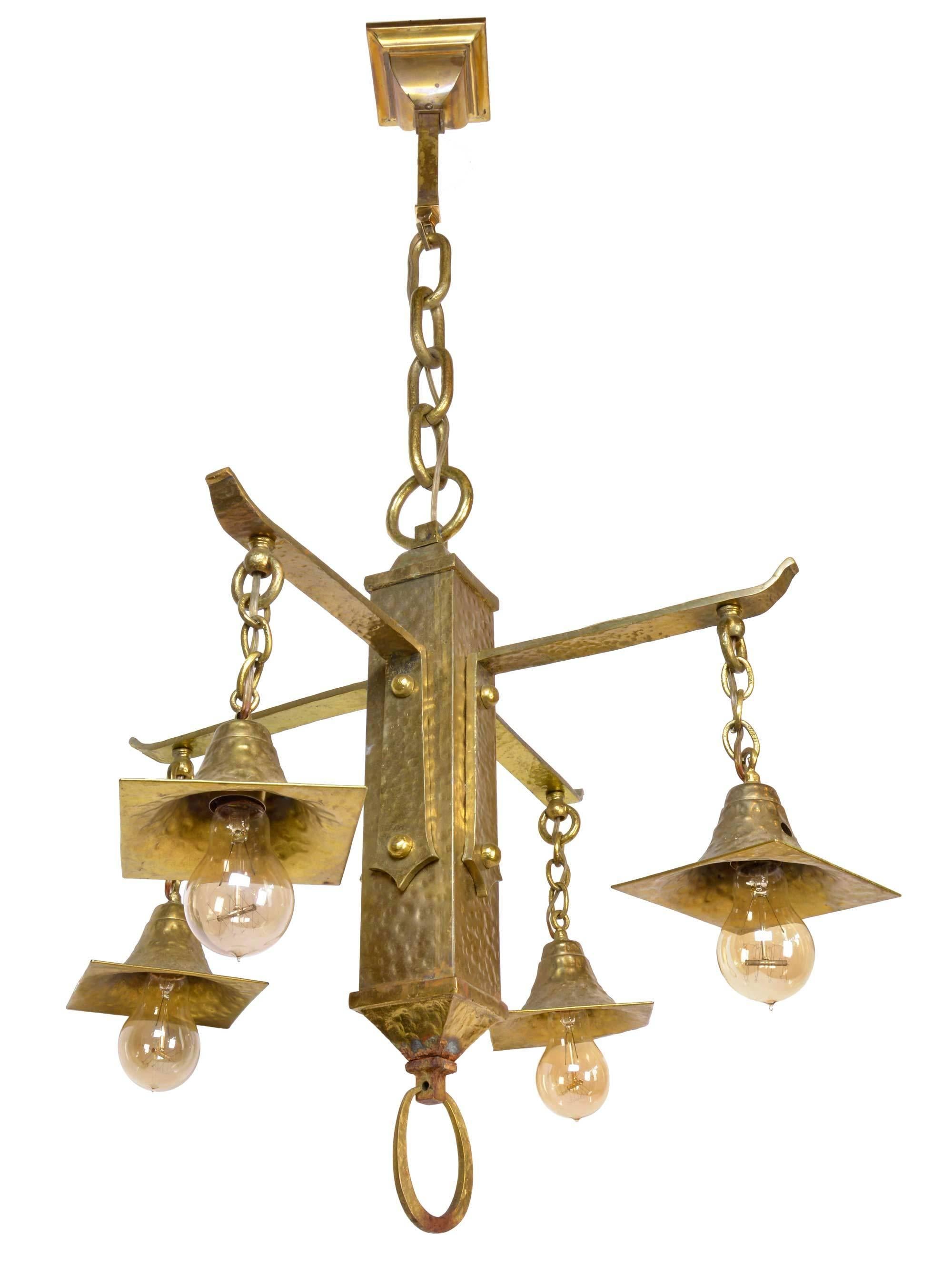 This stunning hammered brass Arts & Crafts chandelier features four cast brass arms, a heavy chain and a handsome, elongated loop finial. Made circa 1915, with a polished finish, it is truly a one of a kind piece! 

We find that early antique