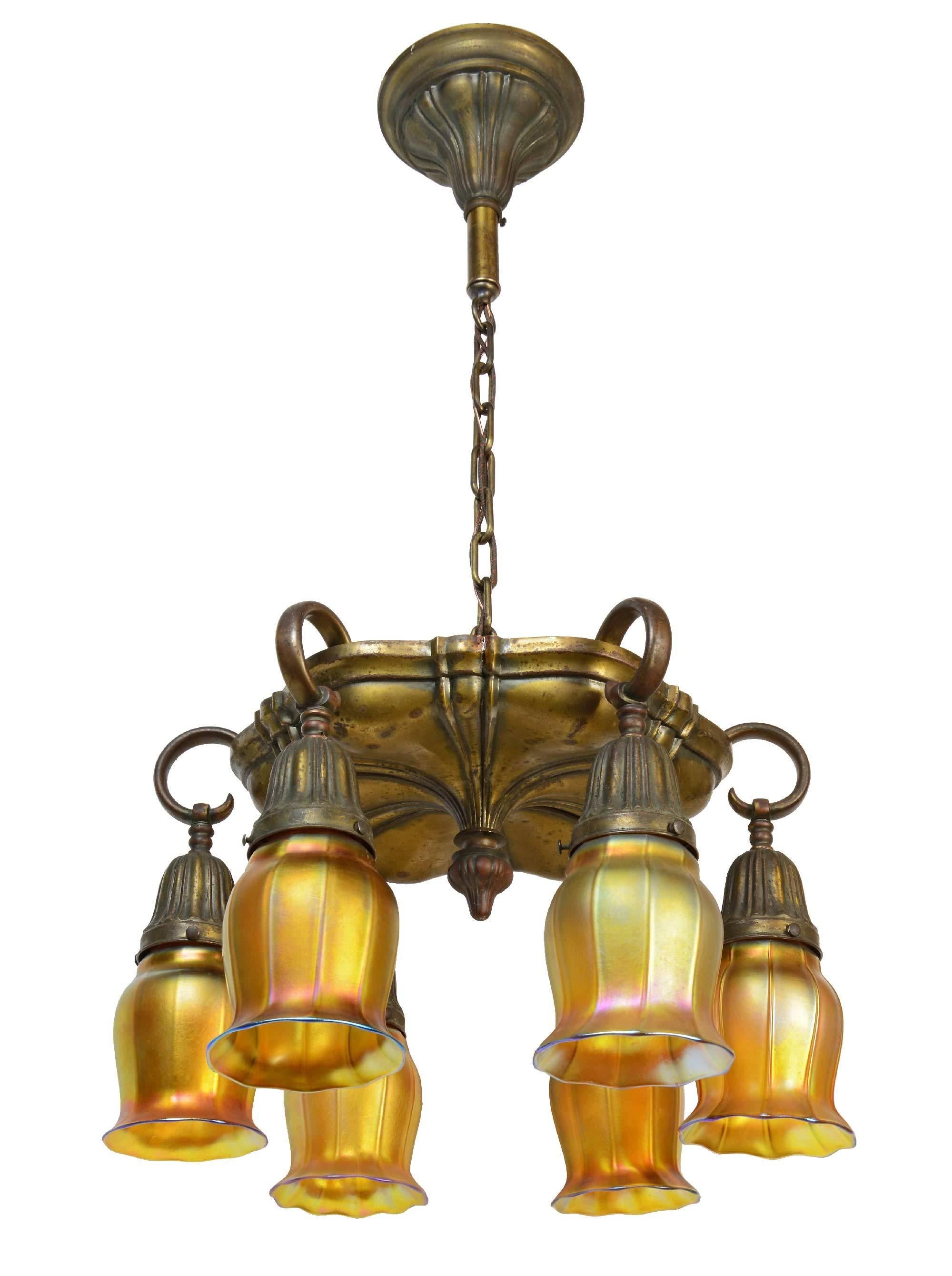 Brass Sheffield chandelier with six ring arms and beautiful iridescent gold Aurene art glass squash blossom shades, stamped Quezal.

Finish: Original.
Six medium sockets.
Fixture without shades: 16
