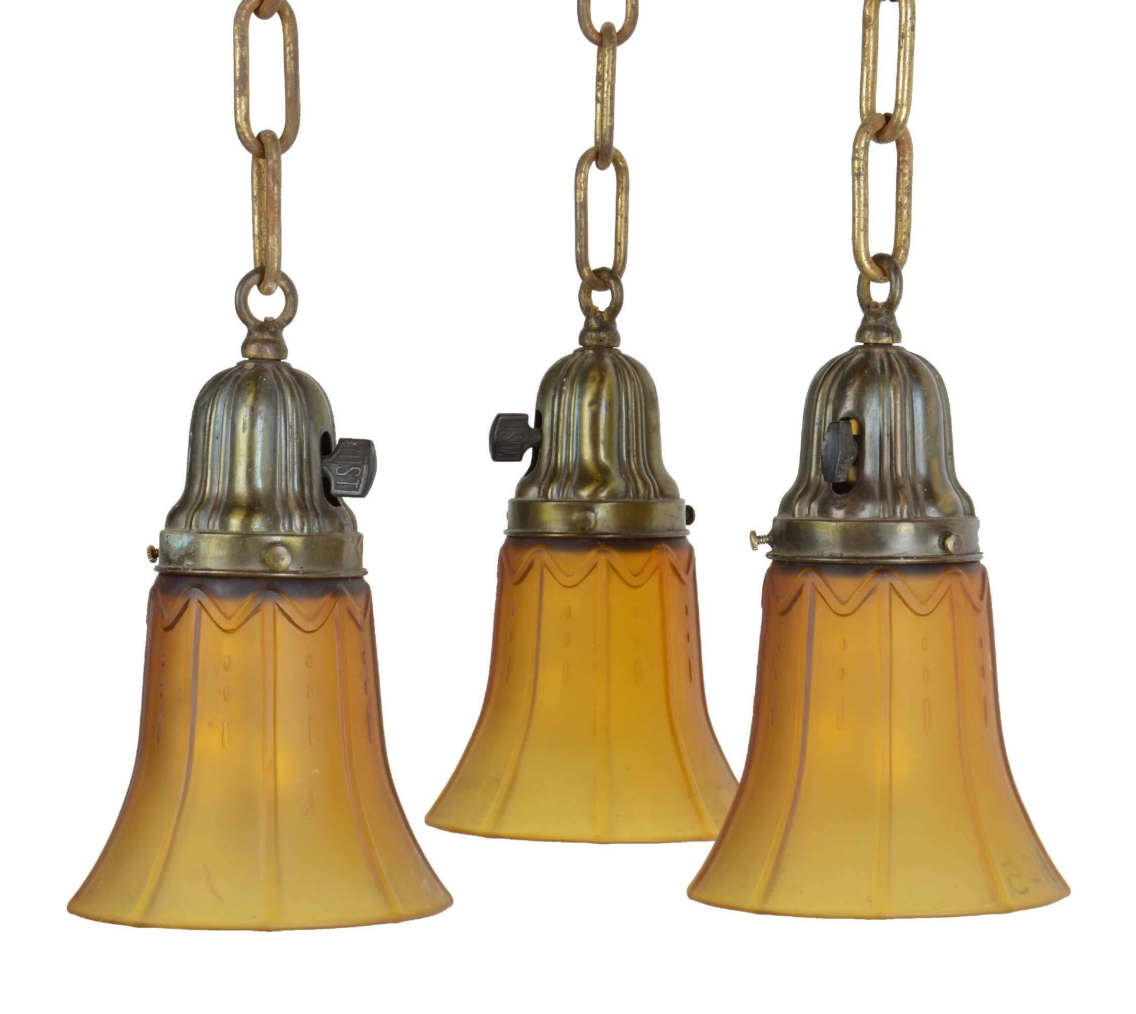 This Sheffield fixture features a large decorative ribbed canopy with acorn finial and three chains that drop down with matching fitters holding antique amber glass shades.

Finish: Original.
Country of origin: USA.
Three medium