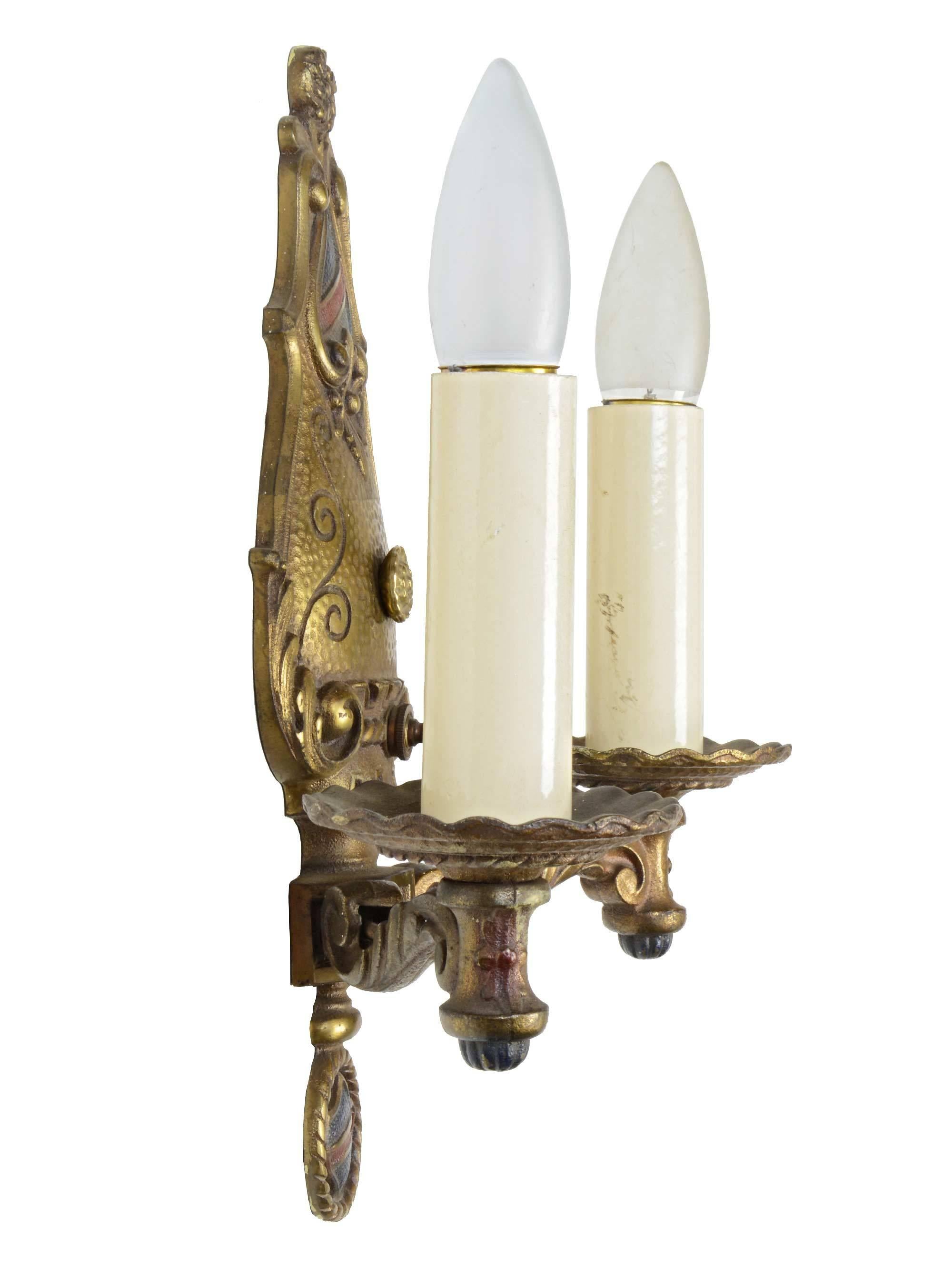 Decorative cast brass two-arm Tudor sconce with leafy arms, scroll and shield backplate and finial.

circa: 1925
Finish: Original
2 medium sockets

We find that early antique lighting was designed as objects of art and we treat each fixture