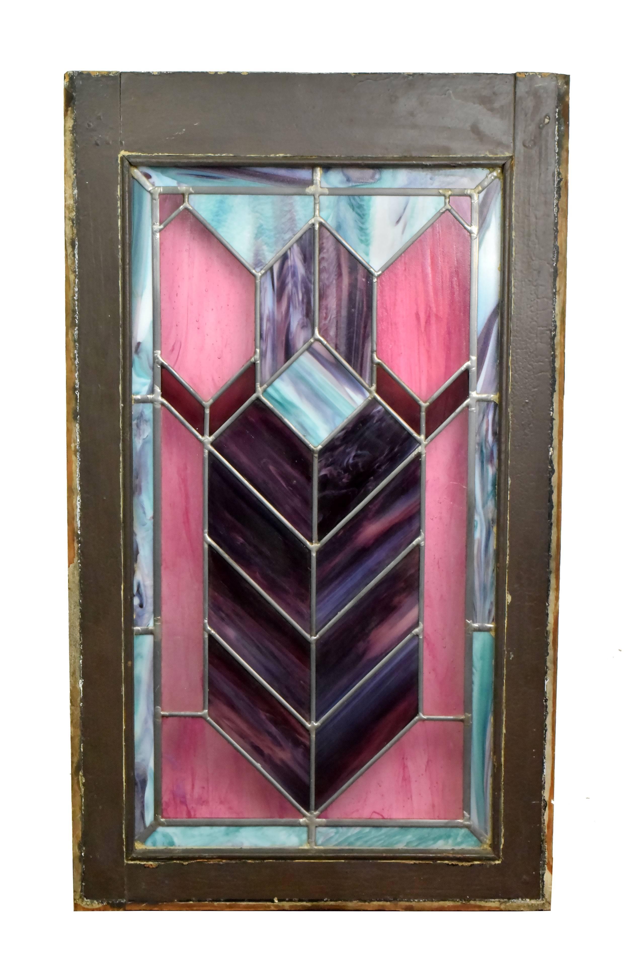 This gorgeous Prairie style stained glass window features purple, pink, and blue-green panels that make up a Classic chevron design. The wood frame is painted dark brown on one side and left unfinished on the other. This would make a great stand