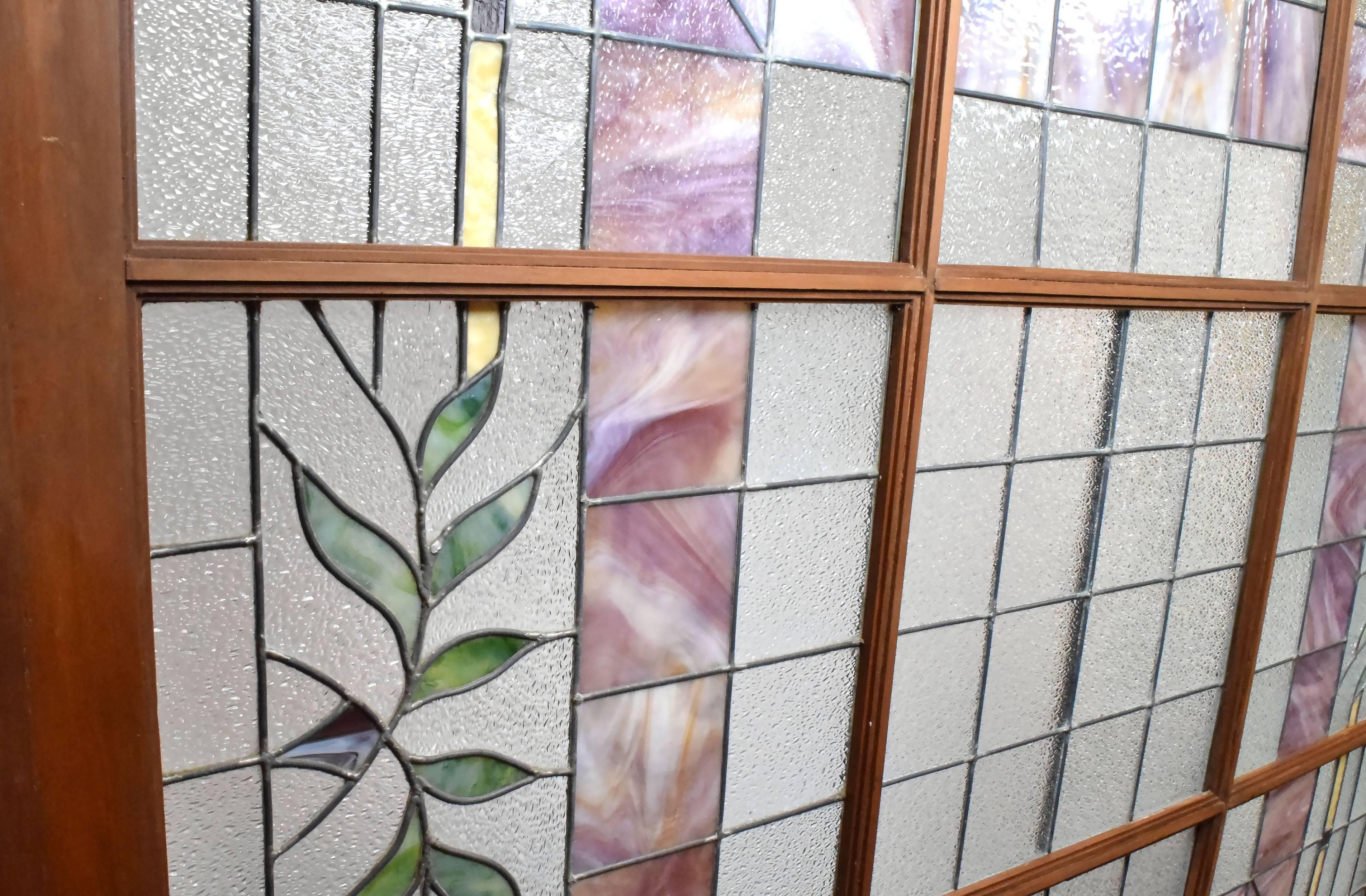 This is an incredible stained glass skylight that spans nearly six feet across. Marbled mauve and coral colored slag glass are surrounded by leafy and pleasing geometric designs, which come to life when lit from behind. The glass is separated into