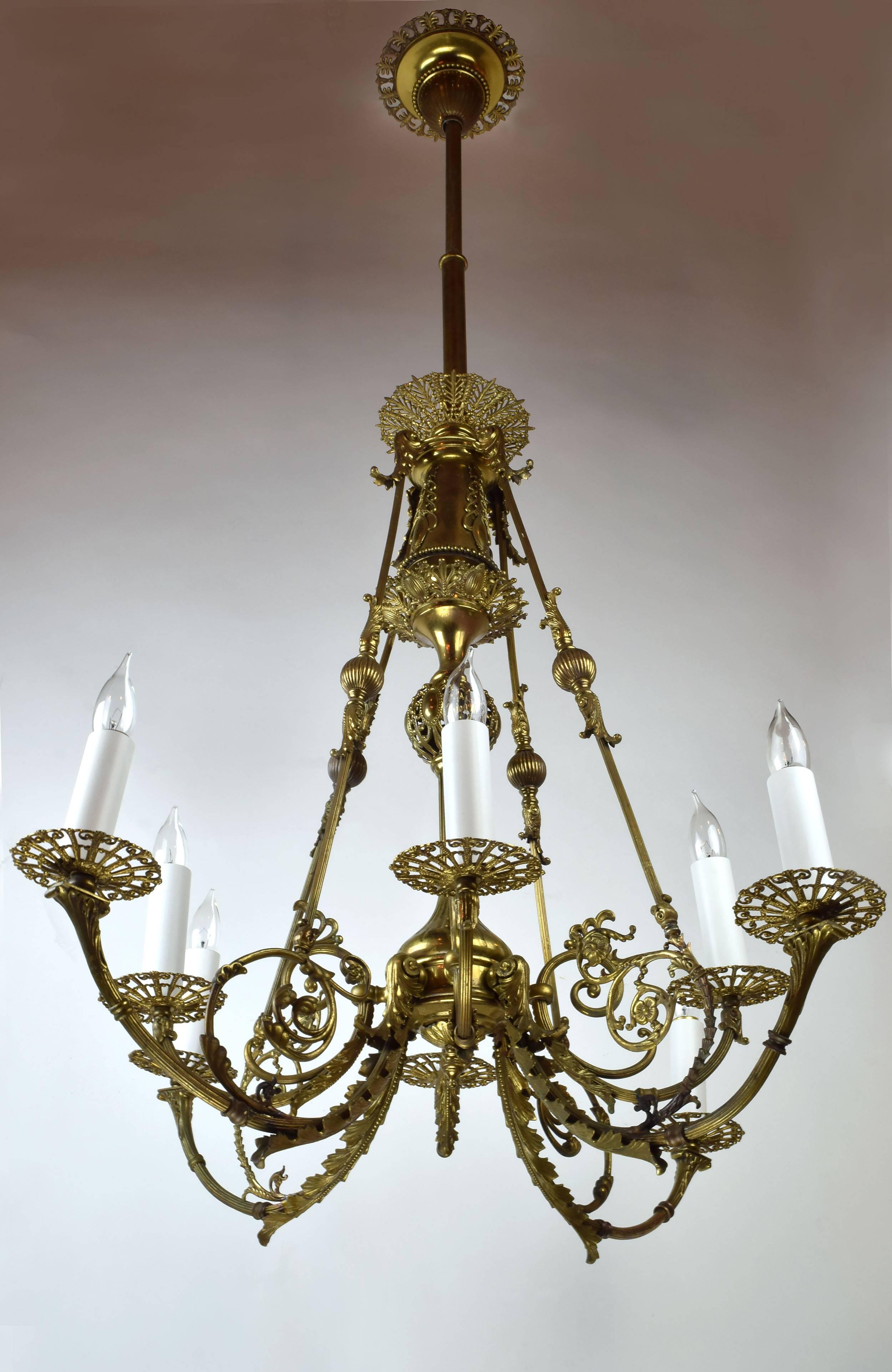 This incredible eight-arm brass chandelier impresses with its ornate organic ornamentation and detailed flourishes. From the canopy down to the candleholders, no surface has gone unadorned, and you may find your eye wandering upwards, drawn to the