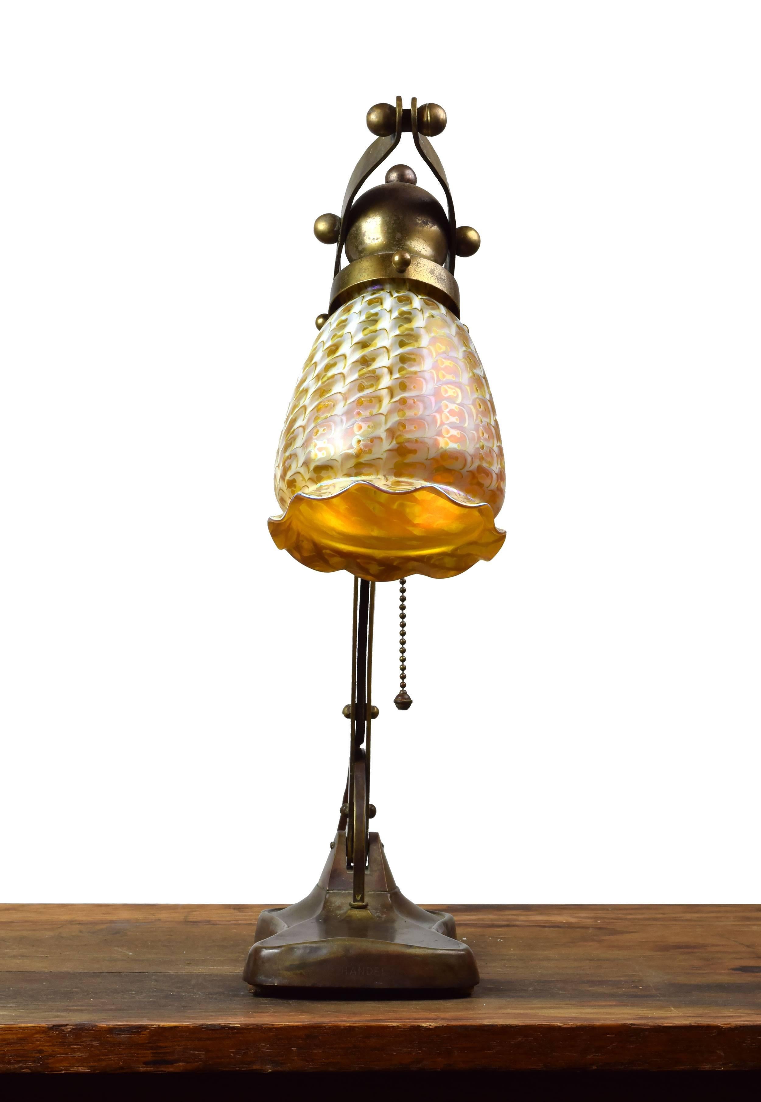 This beautiful cast brass table lamp was manufactured by Handel, one of the early 20th century's premier lighting companies. This fixture features an adjustable swinging arm, allowing you to alter the intensity of light as you see fit. The gently