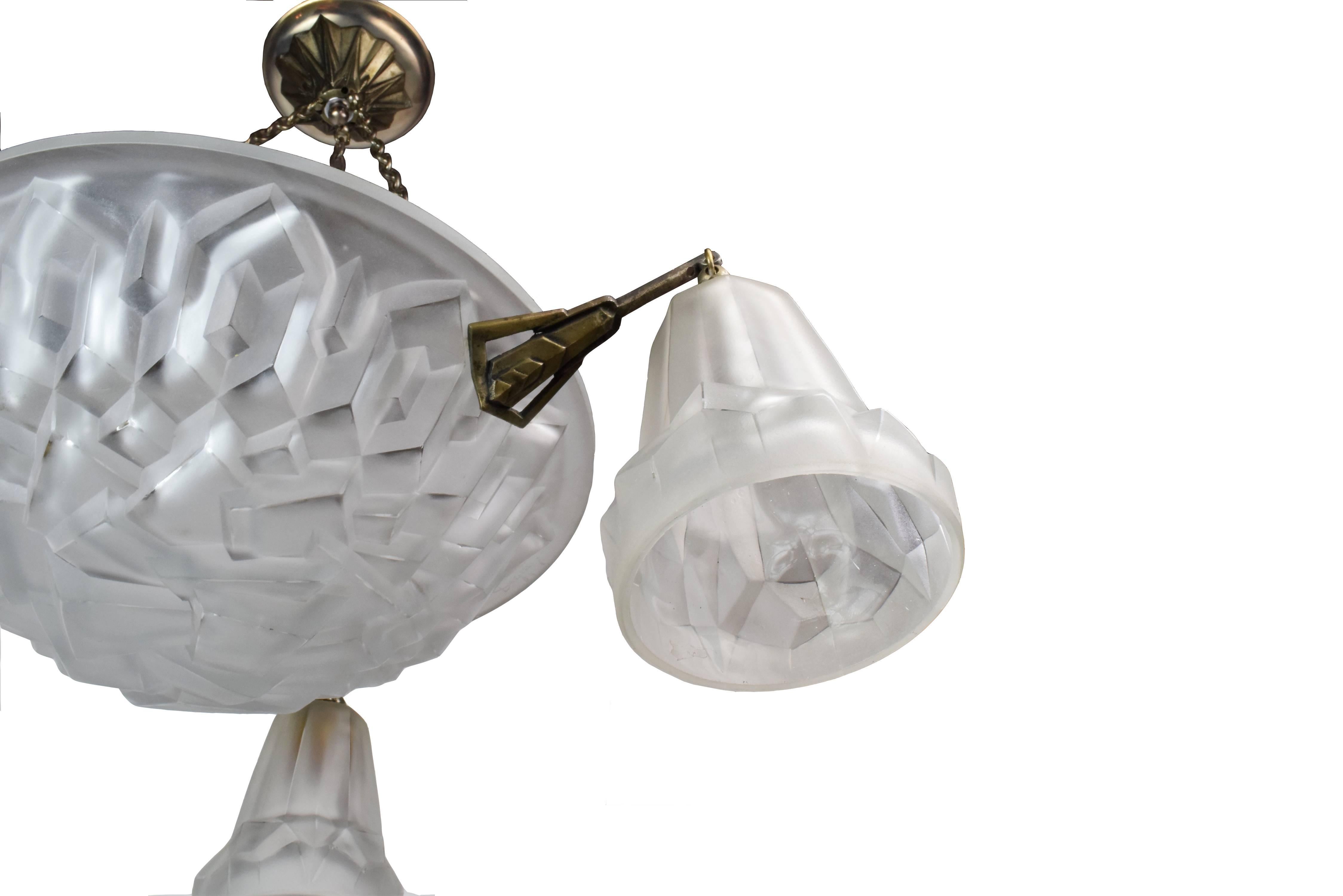 This French Art Deco chandelier with shades is made of beautiful frosted glass and has a carved geometric jagged shape, giving it a very unique, interesting, lovely look that would make it a wonderful addition to any space! It also has an engraved