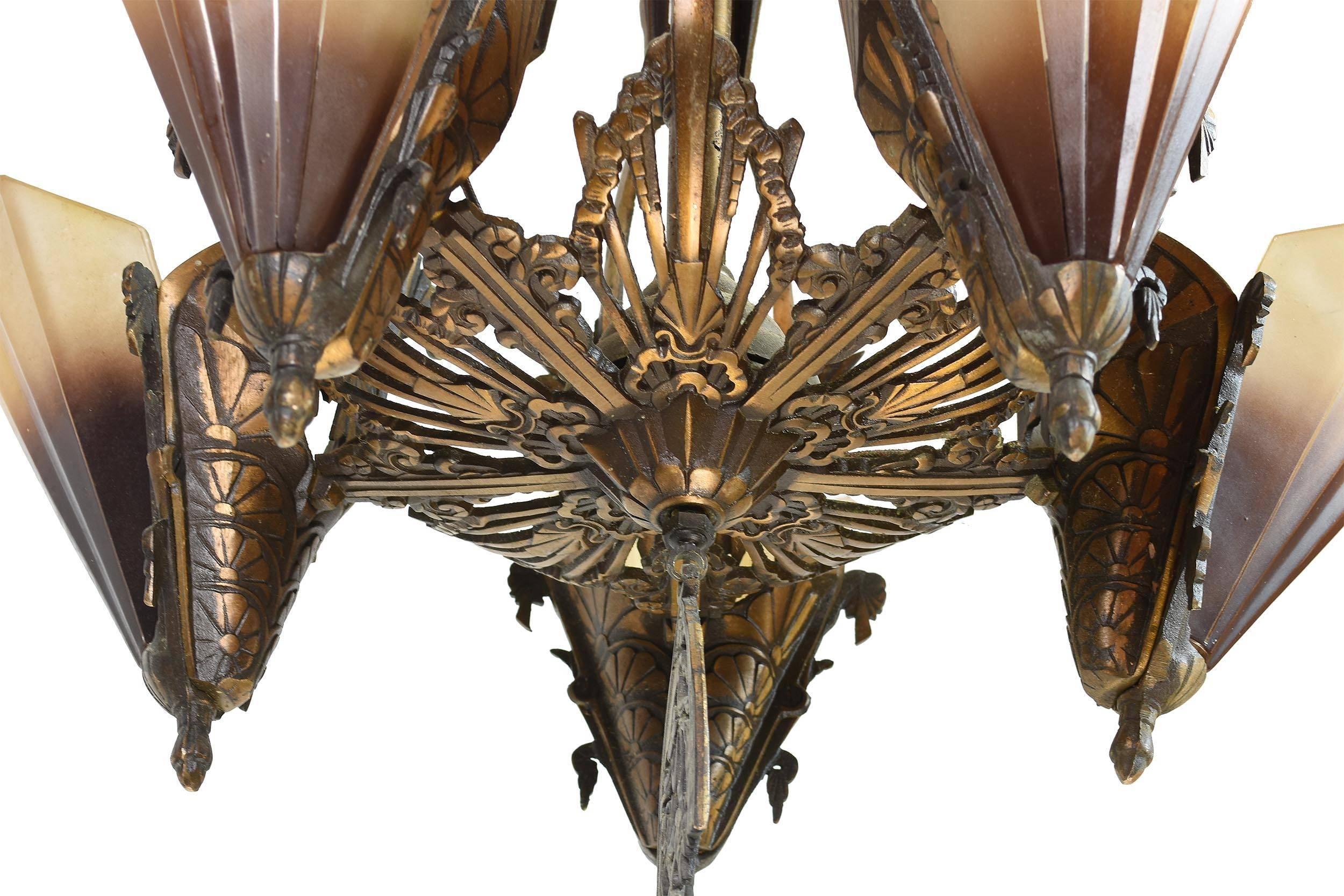 This gorgeous bronze slipper shade chandelier features intricate, stylized floral designs throughout. Truly no surface has gone untouched in terms of detail, and the viewer is rewarded with a plethora of lush patterns from every angle. The elongated