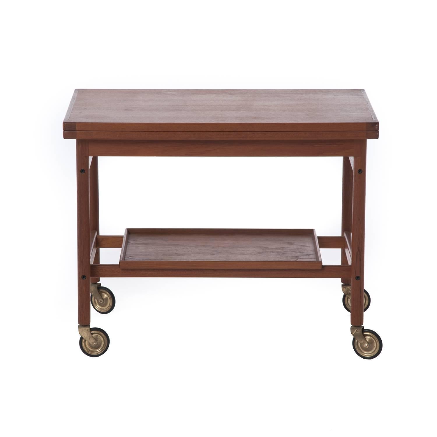 Mid-Century teak Danish bar cart with removable bottom tray and sliding flip-top. The top slides to one side and expands to twice the size, featuring a black laminate on the inner surface conveniently suited for barware. Rolling and portable design
