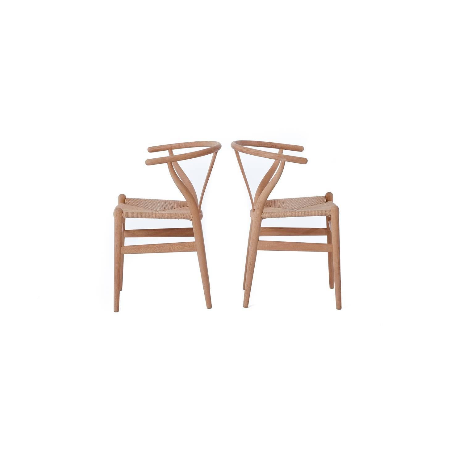 Set of four timeless Hans Wegner Wishbone chairs in soap finished oak with natural paper cord seats.  This lovely set will ship to Continental USA only. 