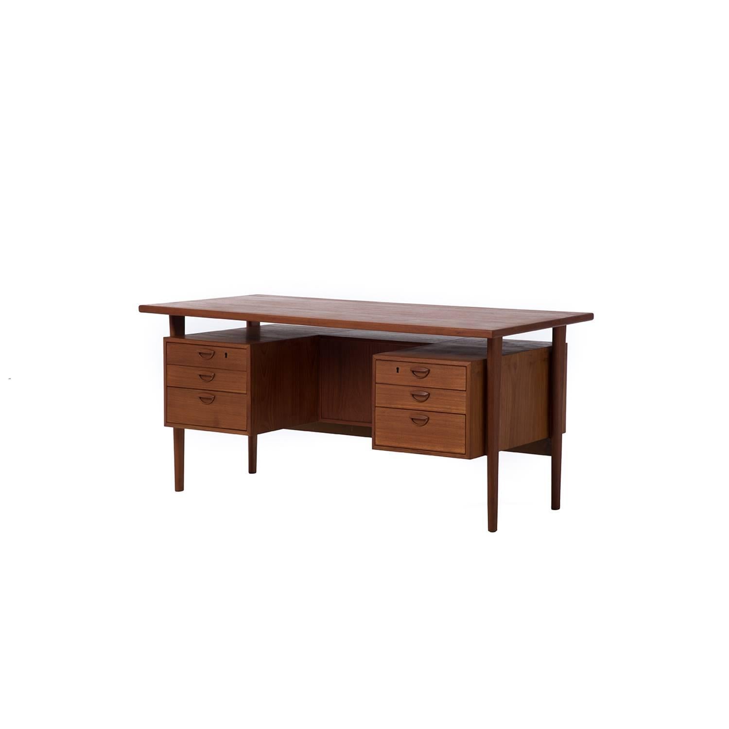 This desk has it all. The expansive work surface rests atop tapered legs from which a series of six drawers are floated. The reverse side includes three open shelves for storage/display.