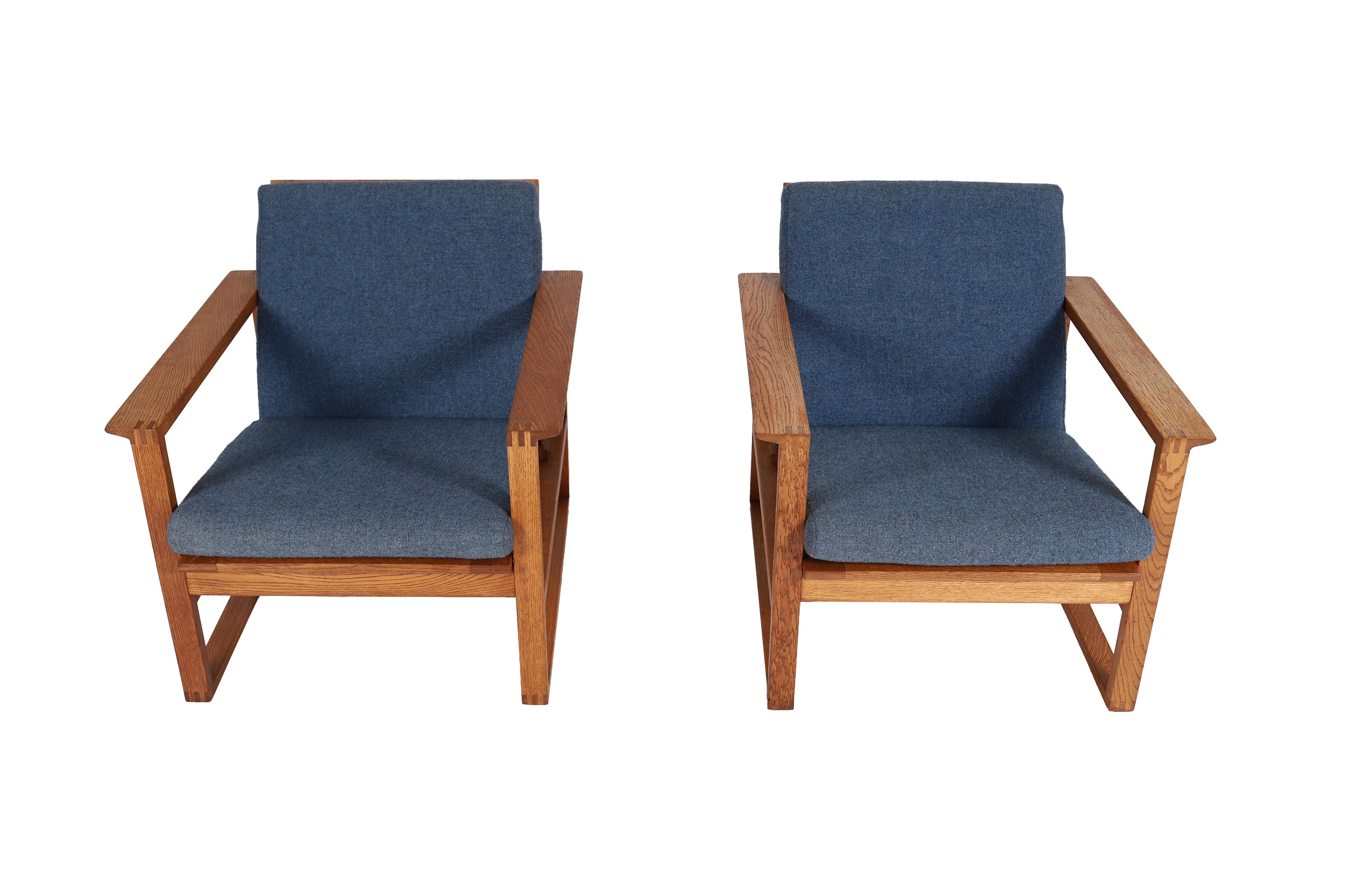 These sled based lounge chairs are made from white oak that has taken on a warm honey glow over time.  Exposed finger joints and gently sweeping inset seat frame add timeless sophistication to this Borge Mogensen design.  Upholstery is a blue grey