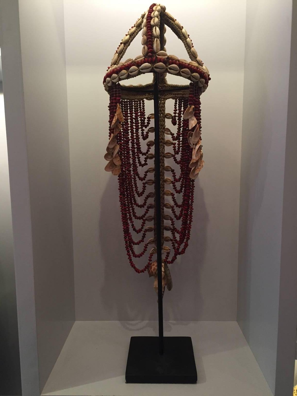 Headdress from Papua New Guinea made from cowrie shells and red seeds applied to traditional macramé fiber. Traditionally this type of ceremonial headdress also served as a form of currency and was often included in wedding dowries. The monetary