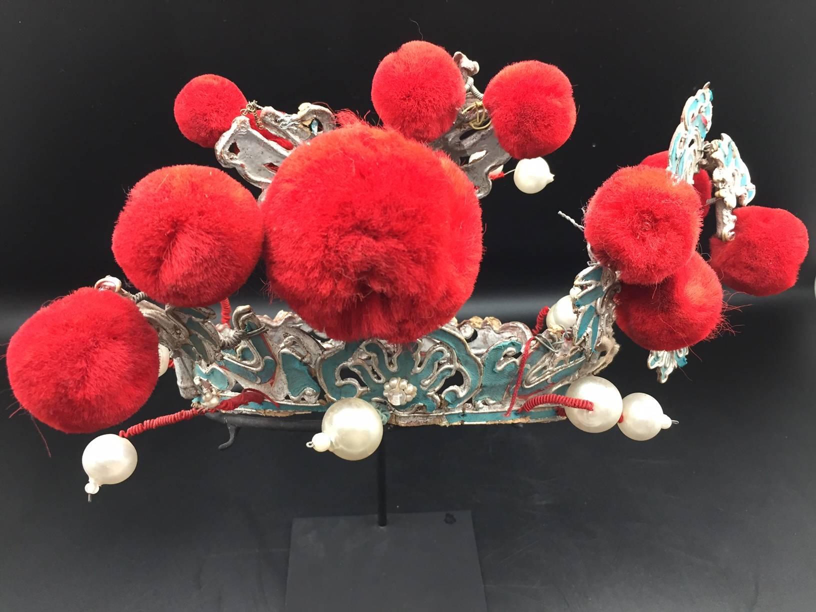Chinese turquoise papier mache and red pom theatre headress, early 20th century, mounted on a custom, black painted metal base.